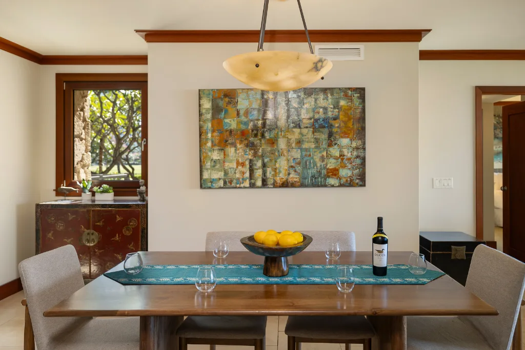 Comedor con una mesa de madera, arte colorido en la pared y una lámpara colgante.