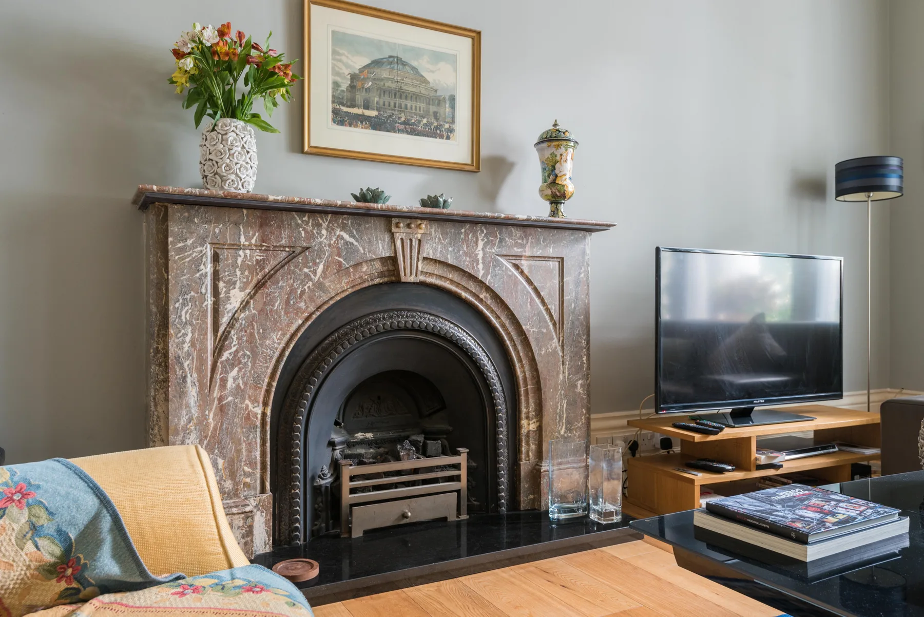 Una sala de estar con una chimenea ornamentada, asientos y un televisor.