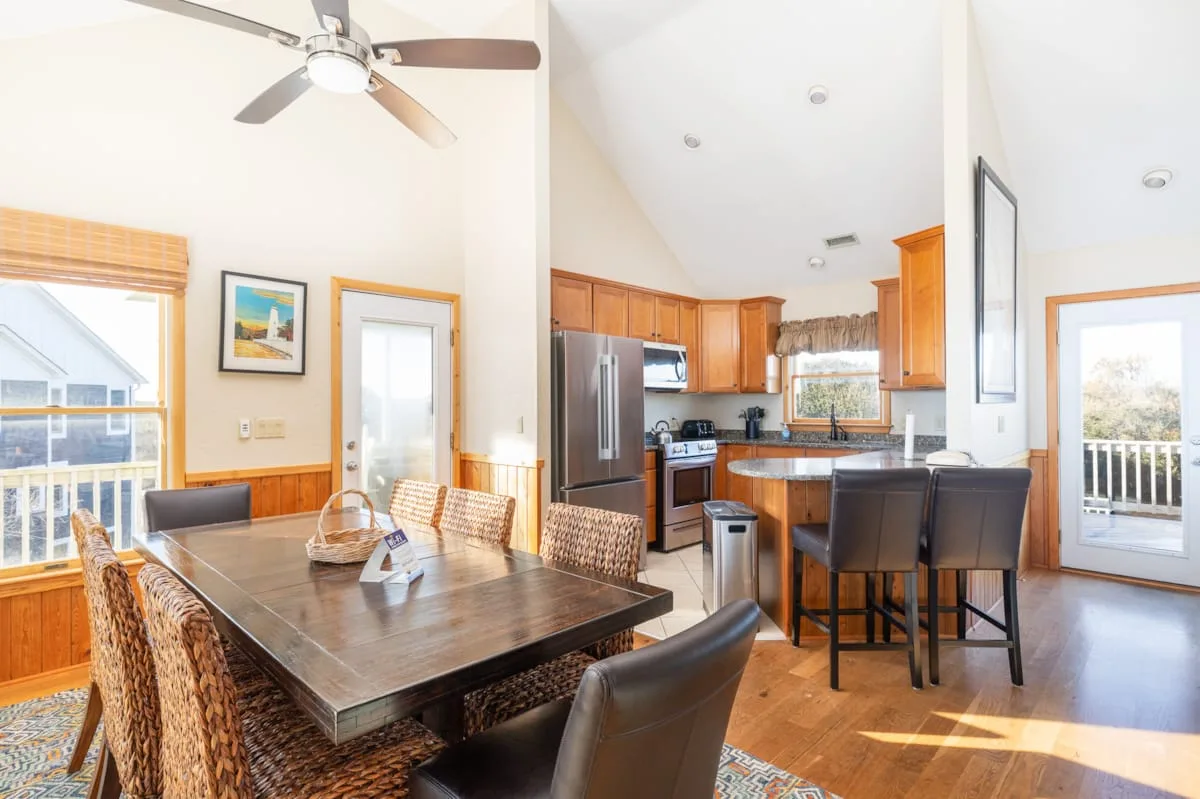 An open-plan dining area and kitchen with wooden cabinetry and a dining table.