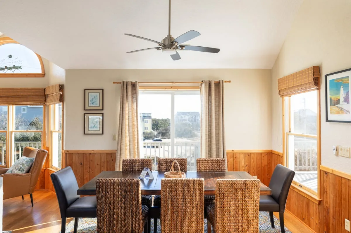 A dining area with a table and chairs beside large windows.