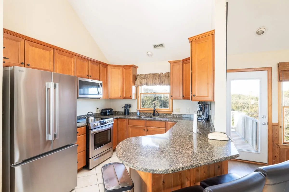 A bright kitchen with wooden cabinets, stainless steel appliances, and a large island.