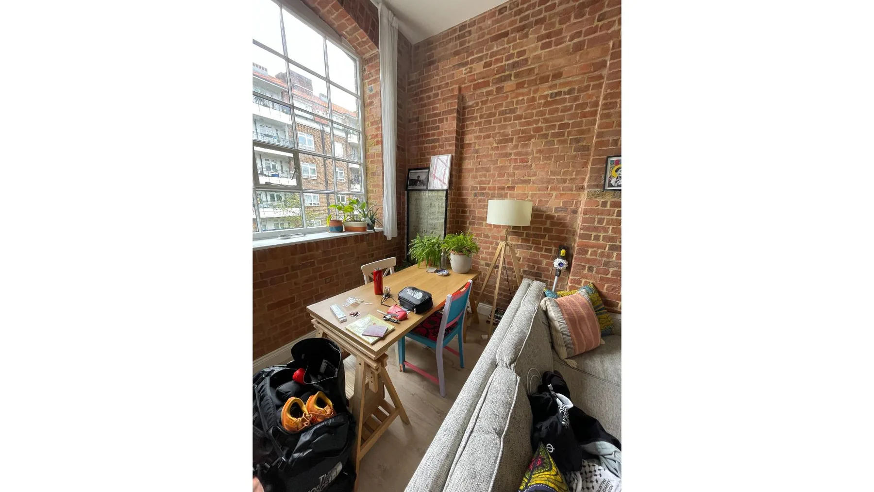 A brick-walled living area with a large window, a table, and seating.