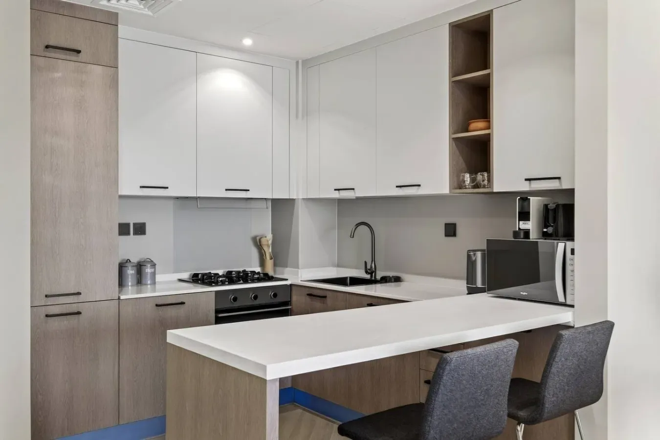 Una cocina moderna con gabinetes blancos, una encimera y asientos de barra.