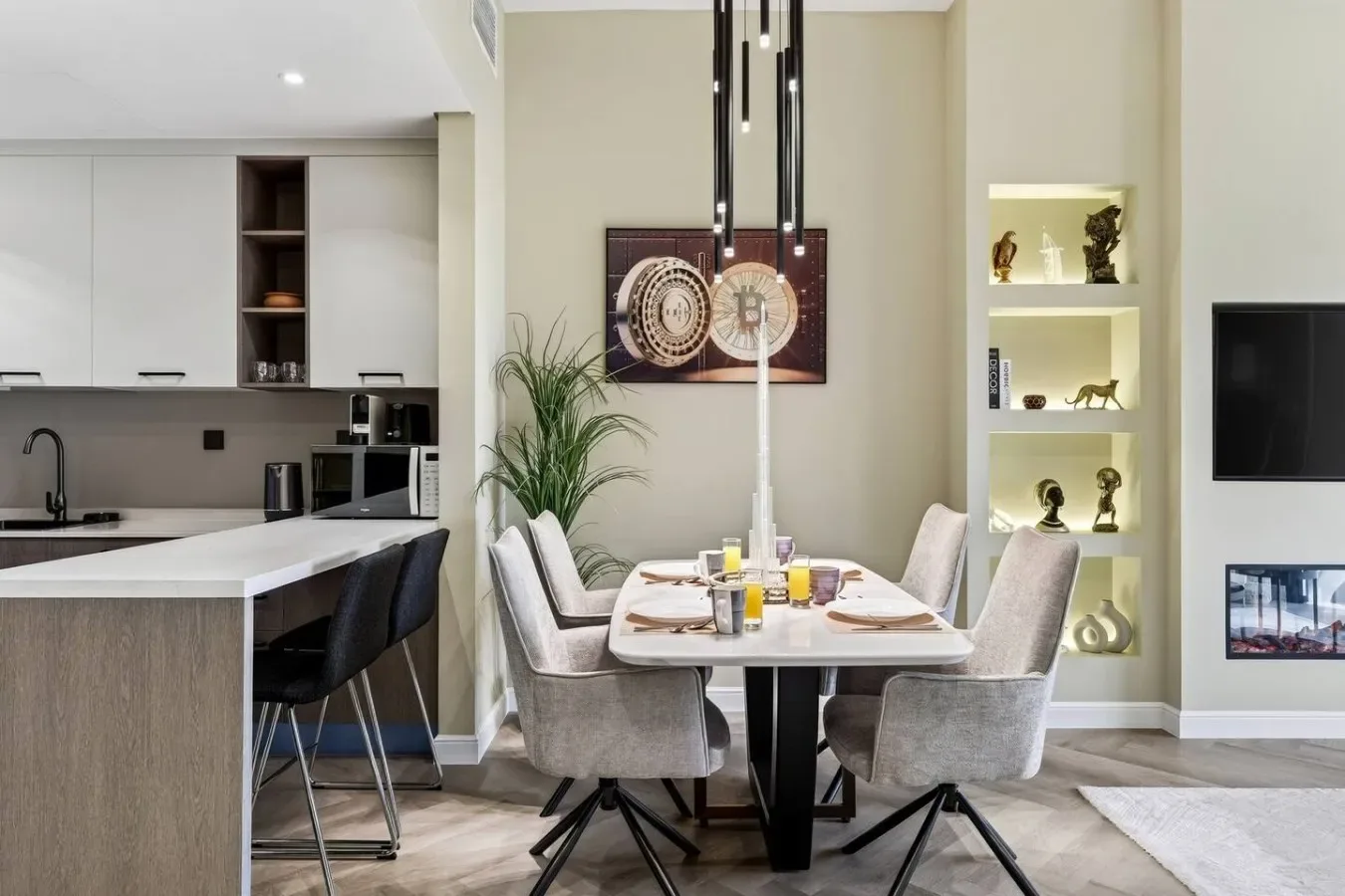 A dining area with a table and upholstered seating beside an open kitchen.