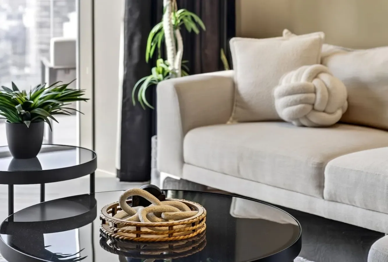 A bright living room with a light-colored sofa and a round black coffee table.
