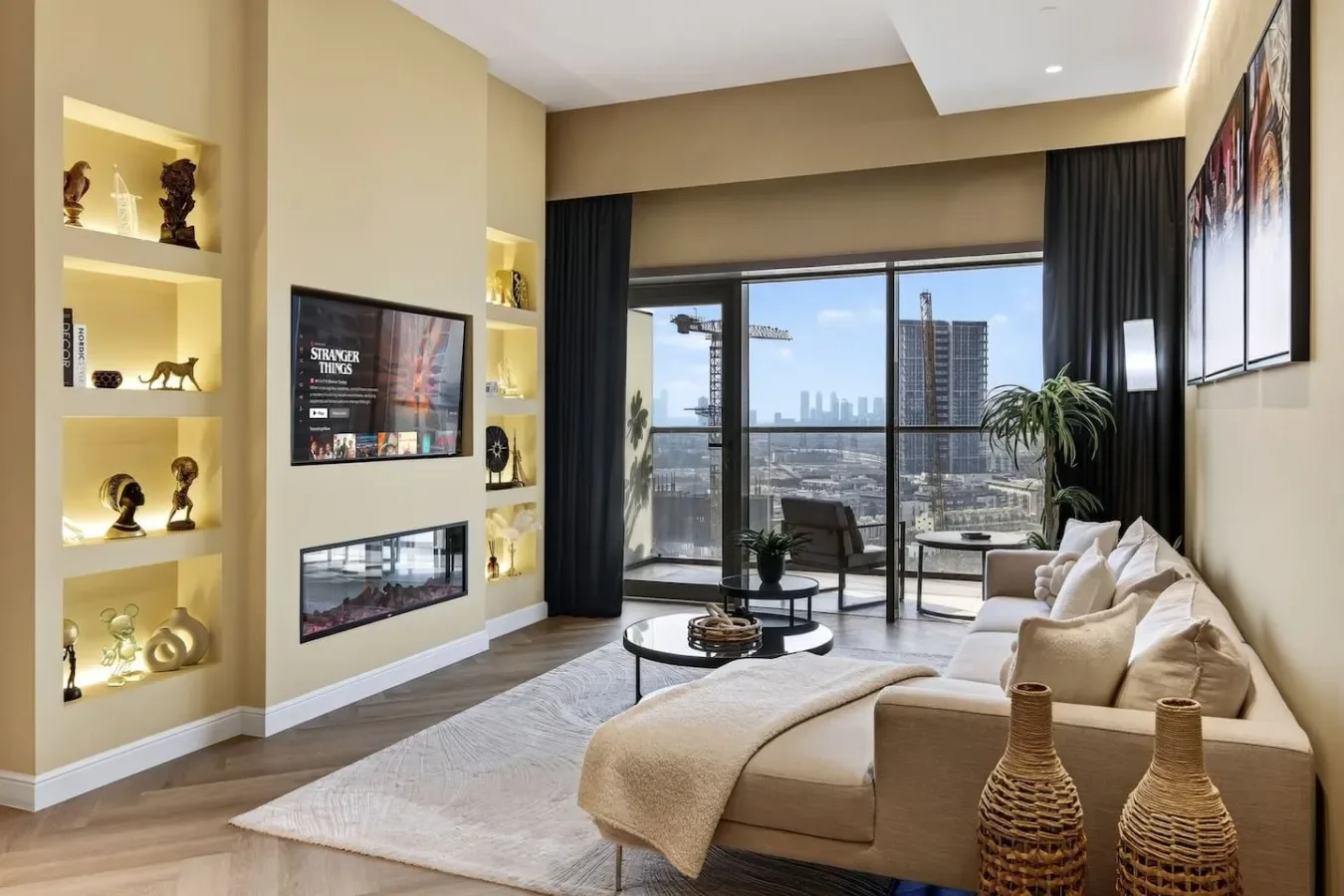 Una sala de estar moderna con asientos, estantes decorativos y grandes ventanas con vista a la ciudad.