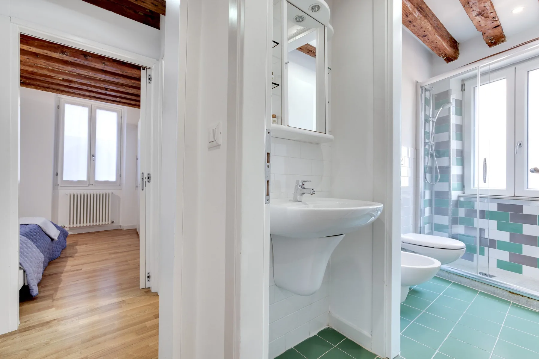 A view through the hallway shows a bedroom and a bathroom with a sink.
