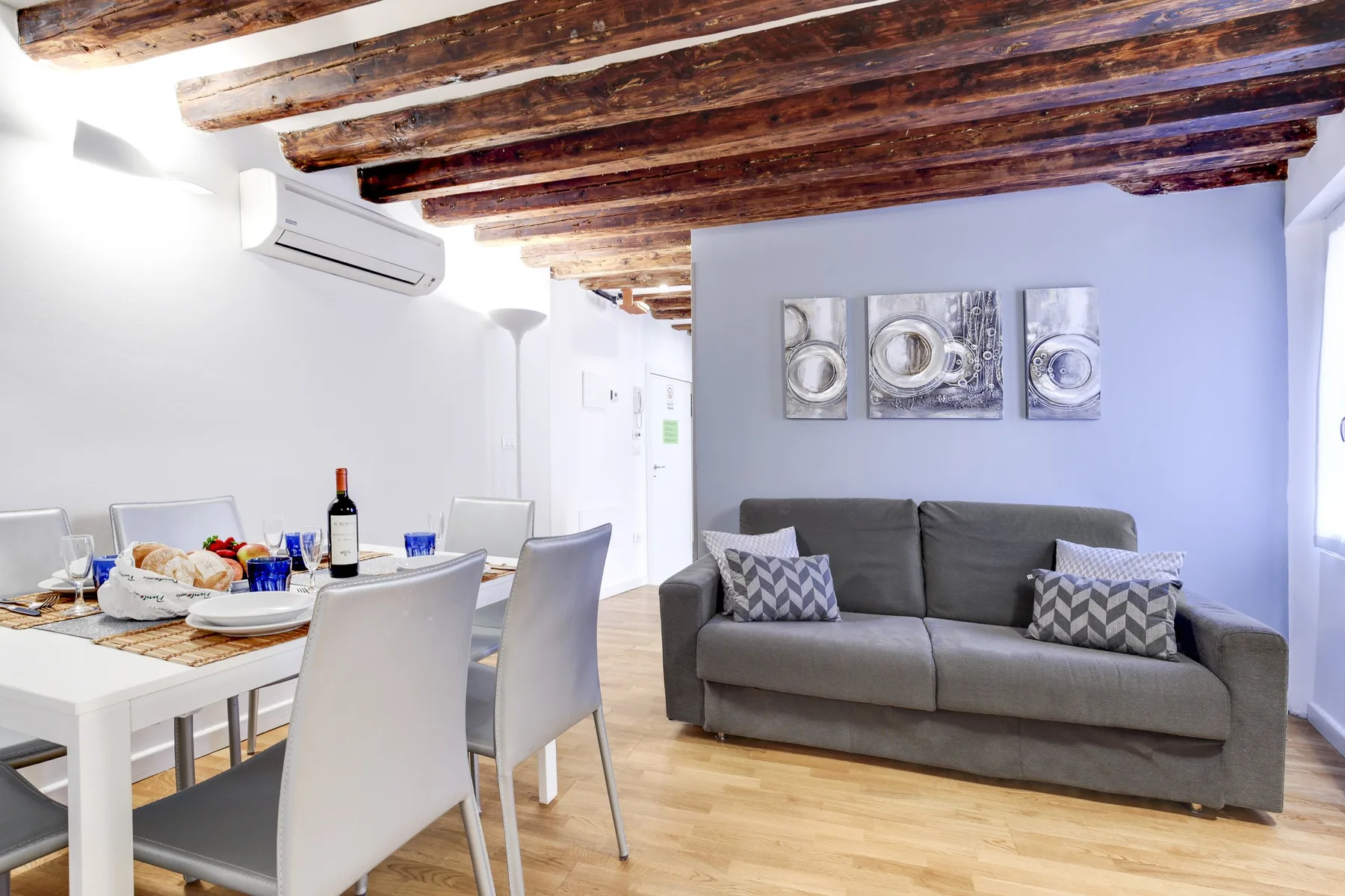 A living and dining area with a gray sofa and a set dining table.