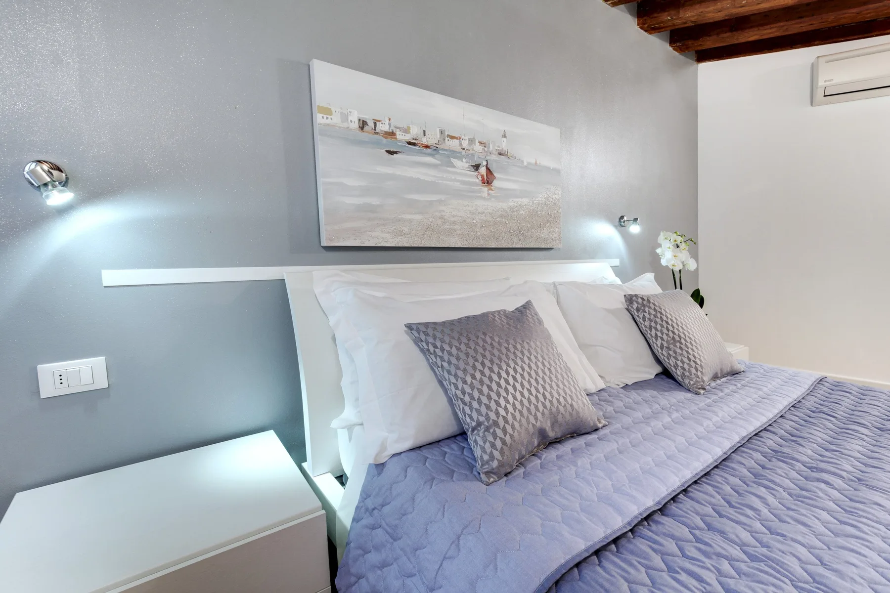 A bedroom with a neatly made bed and framed artwork above the headboard.