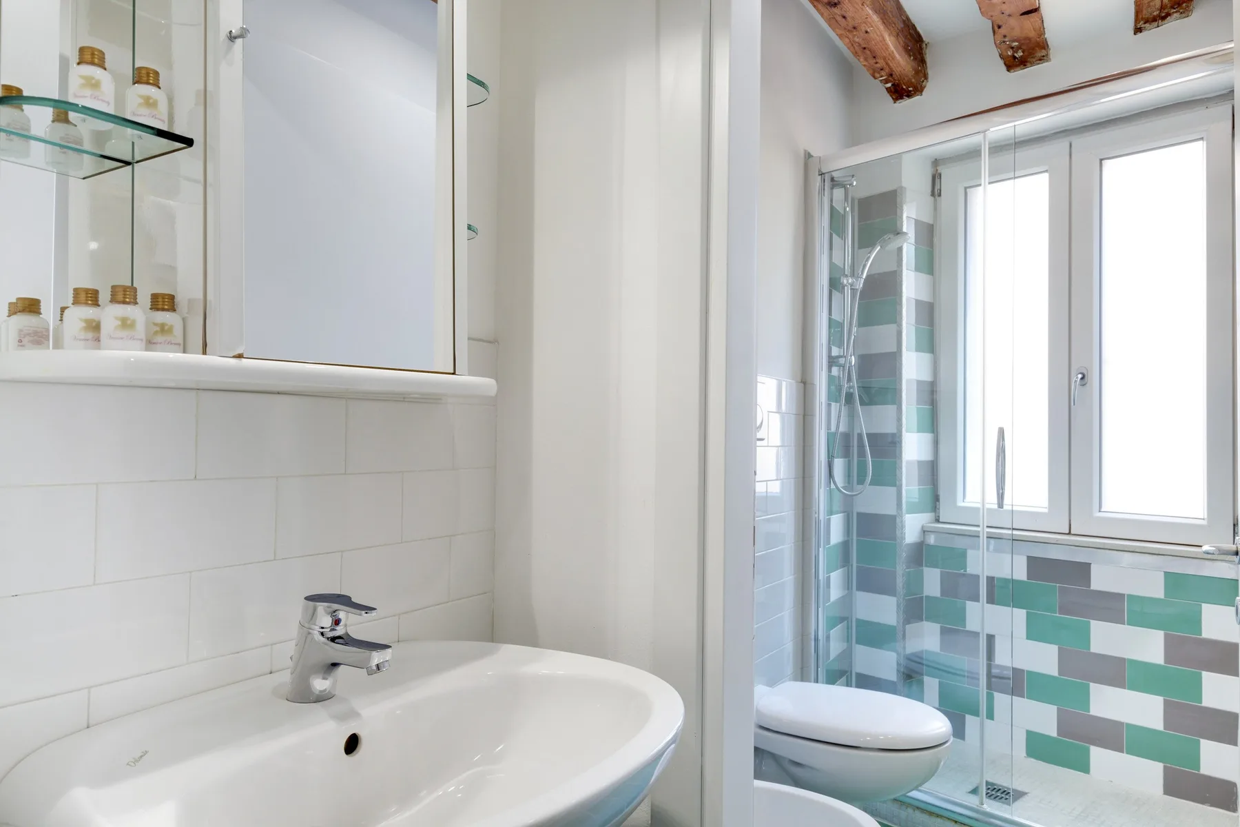 A bright bathroom with a sink, toilet, and glass-enclosed shower.