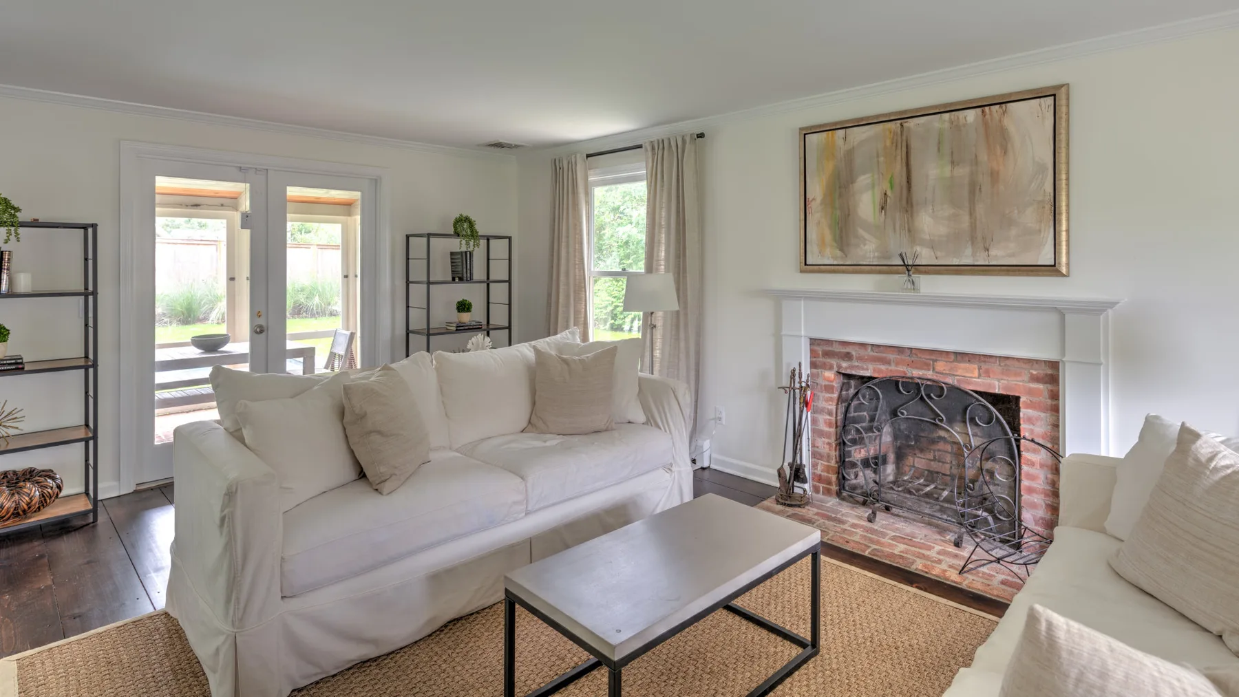 Una sala luminosa tiene asientos blancos, una chimenea y una obra enmarcada.