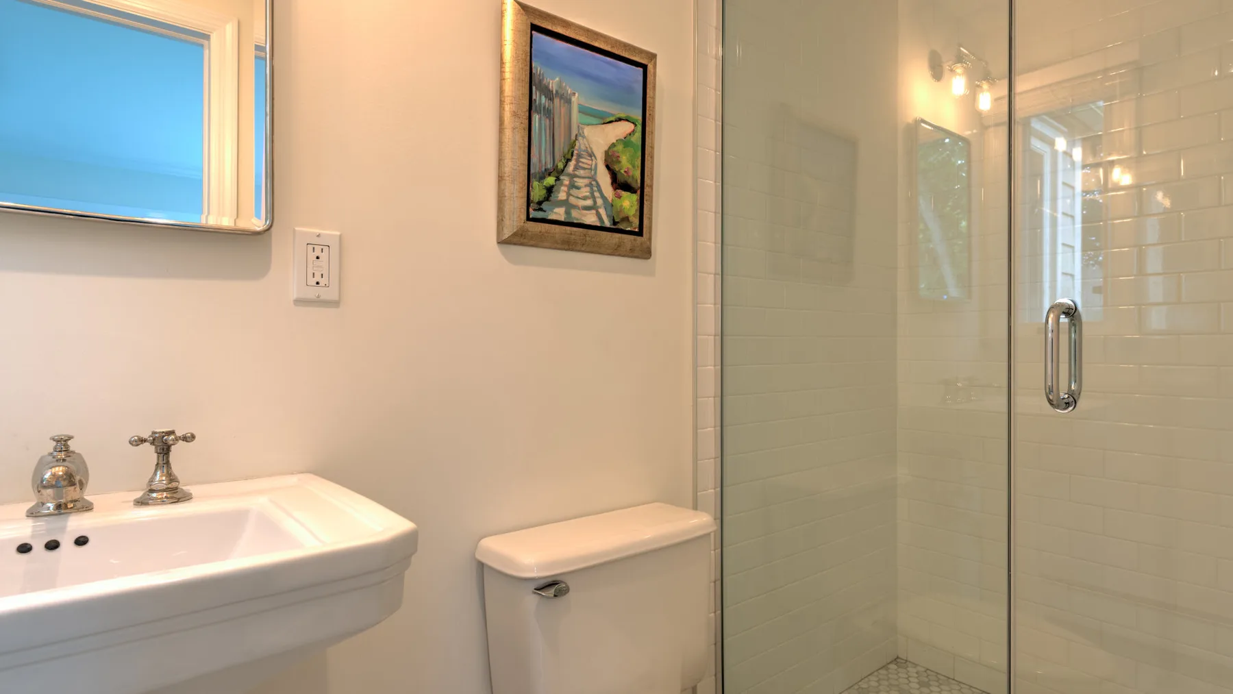 Un baño con lavabo y ducha con mampara de vidrio.