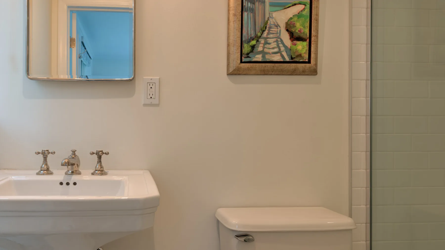 Un baño con lavabo de pared, inodoro y zona de ducha con azulejos.