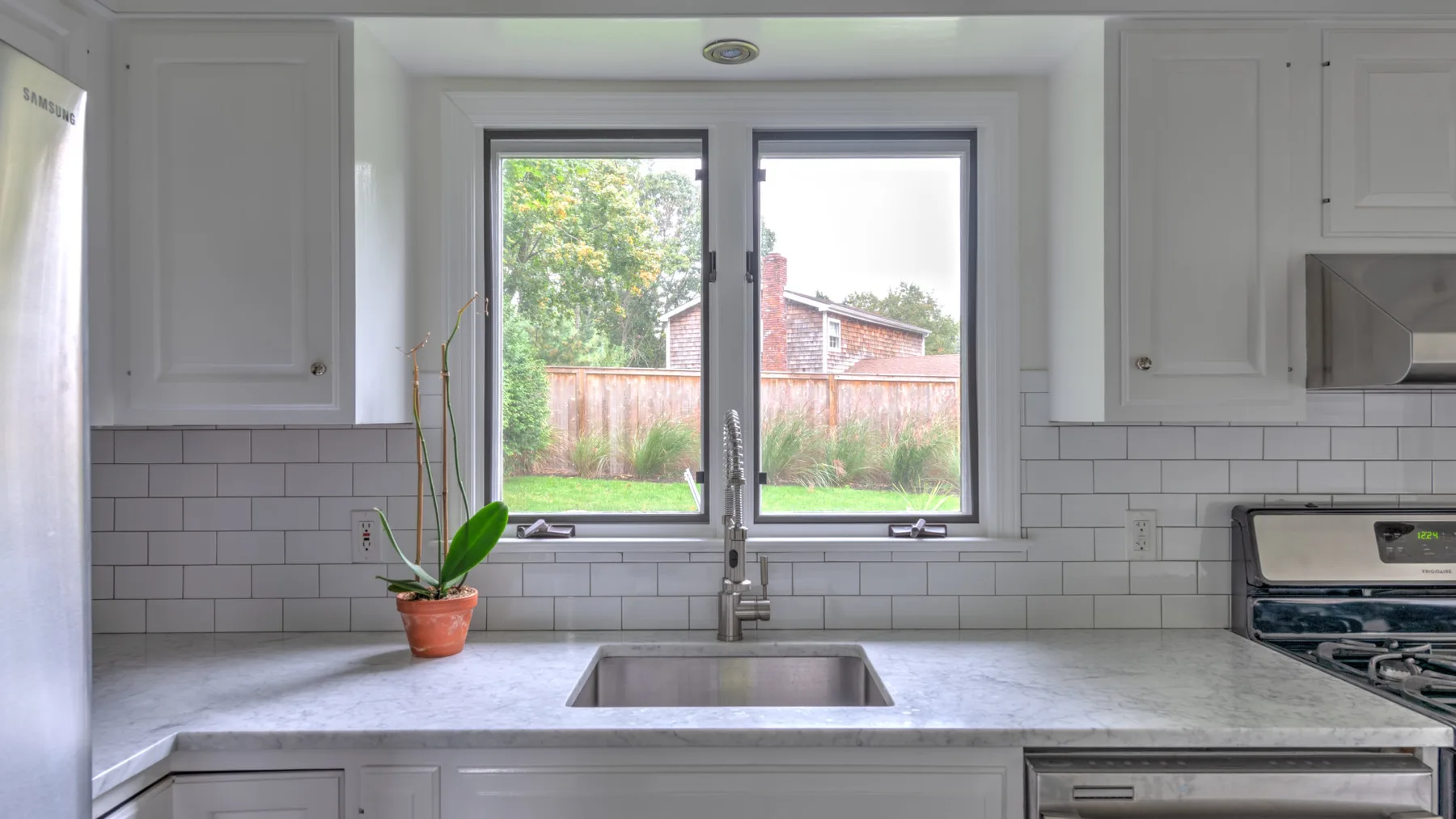 Una cocina luminosa con un fregadero bajo una ventana grande.