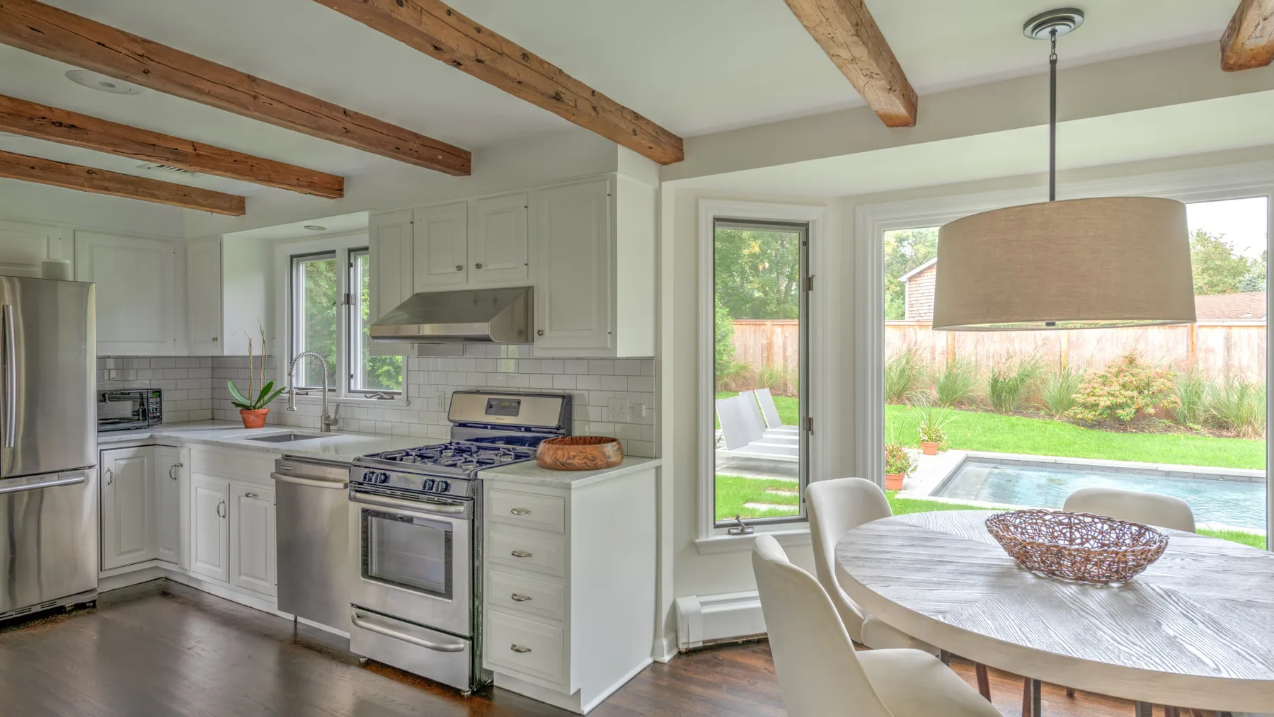 Una luminosa cocina con comedor da a un jardín y una piscina.