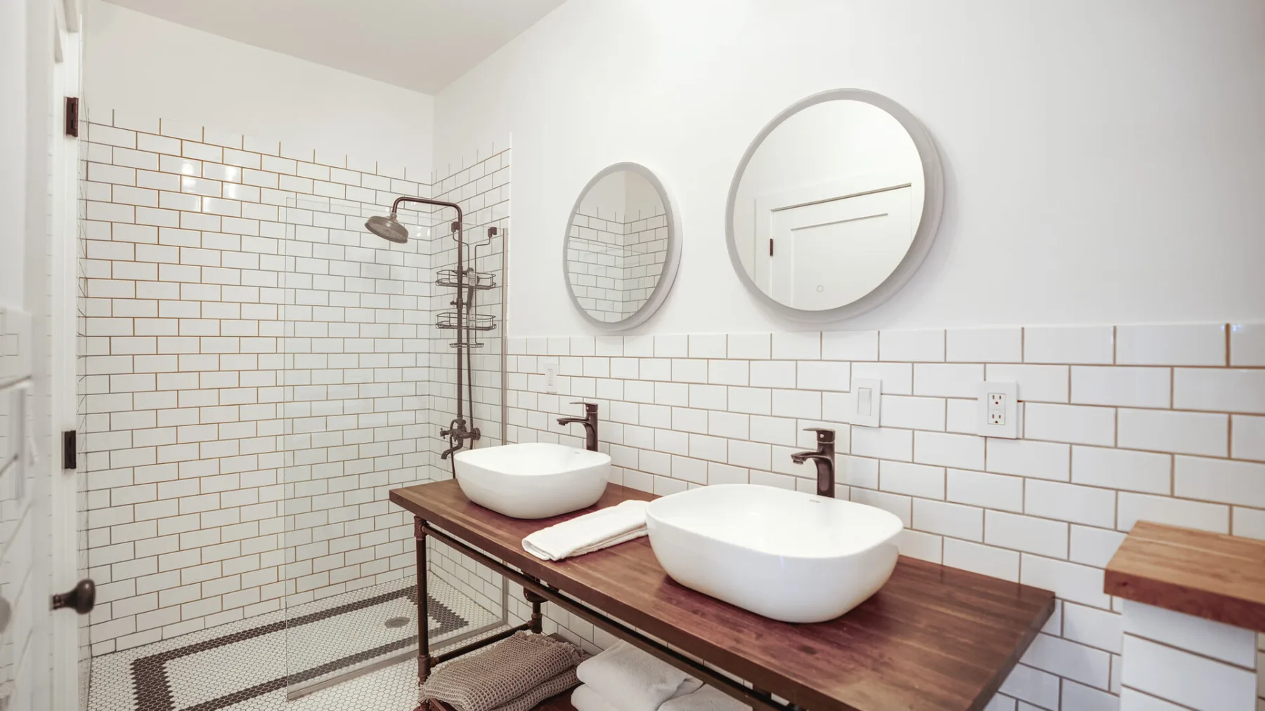 Un baño con dos lavabos blancos sobre una encimera de madera.