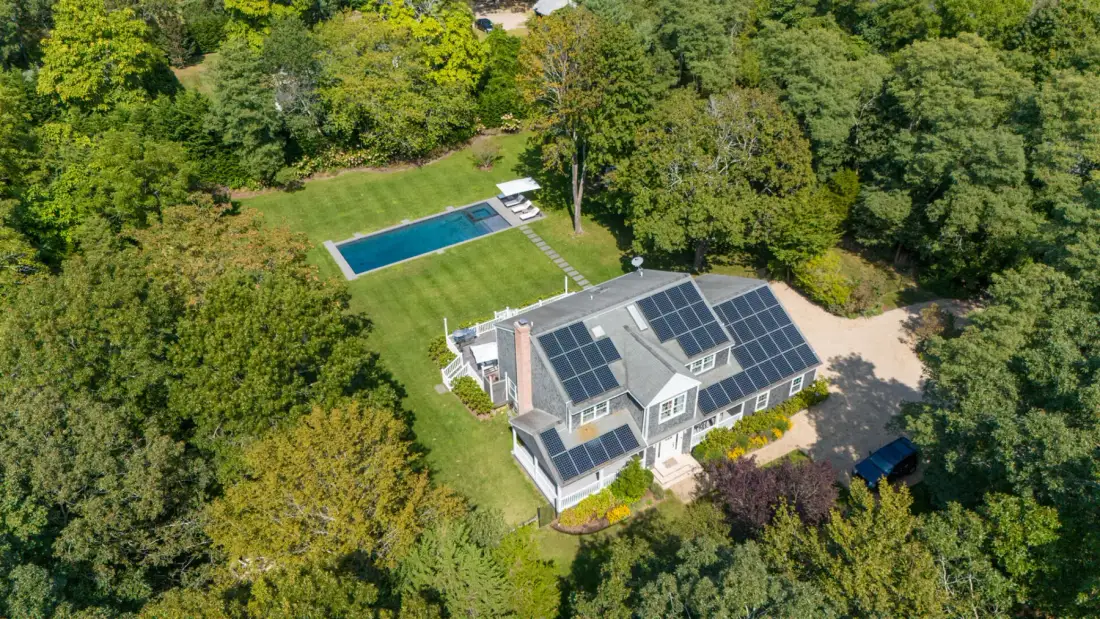 Vista aérea de una casa con paneles solares en el techo y una piscina.