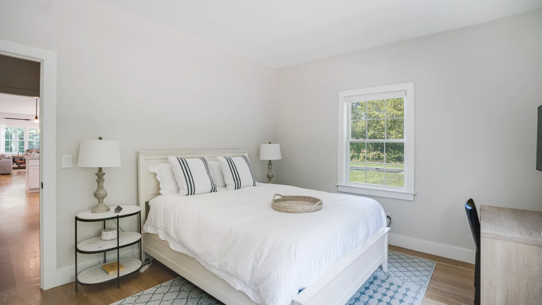 Un dormitorio luminoso con una cama bien tendida y una ventana con vista a la vegetación.