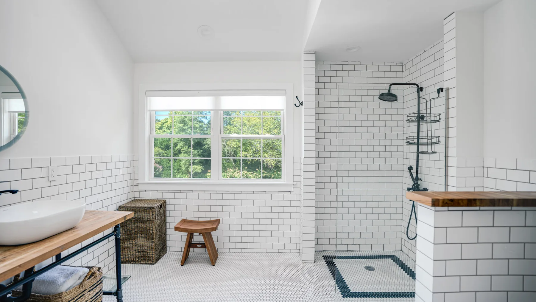 Un baño luminoso con ventana, lavabo sobre encimera y zona de ducha con azulejos.