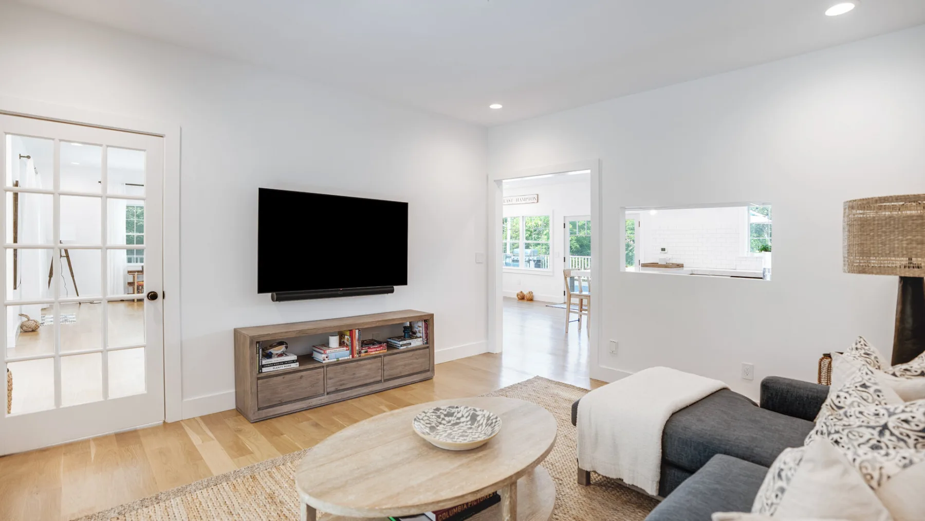 Una sala de estar luminosa con televisor, asientos y una mesa de centro.