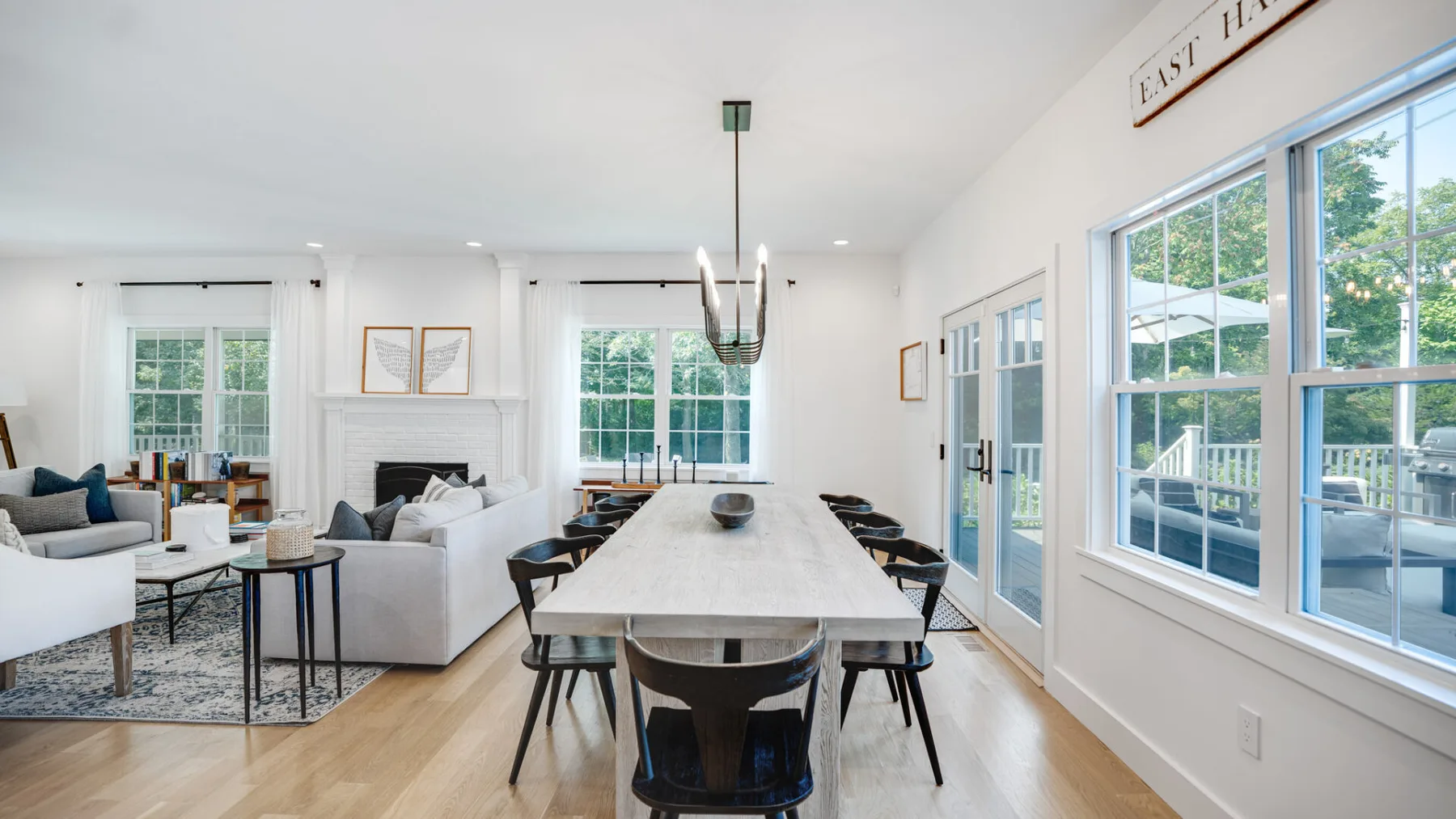 Un comedor luminoso con una mesa larga junto a grandes ventanas y puertas de vidrio.