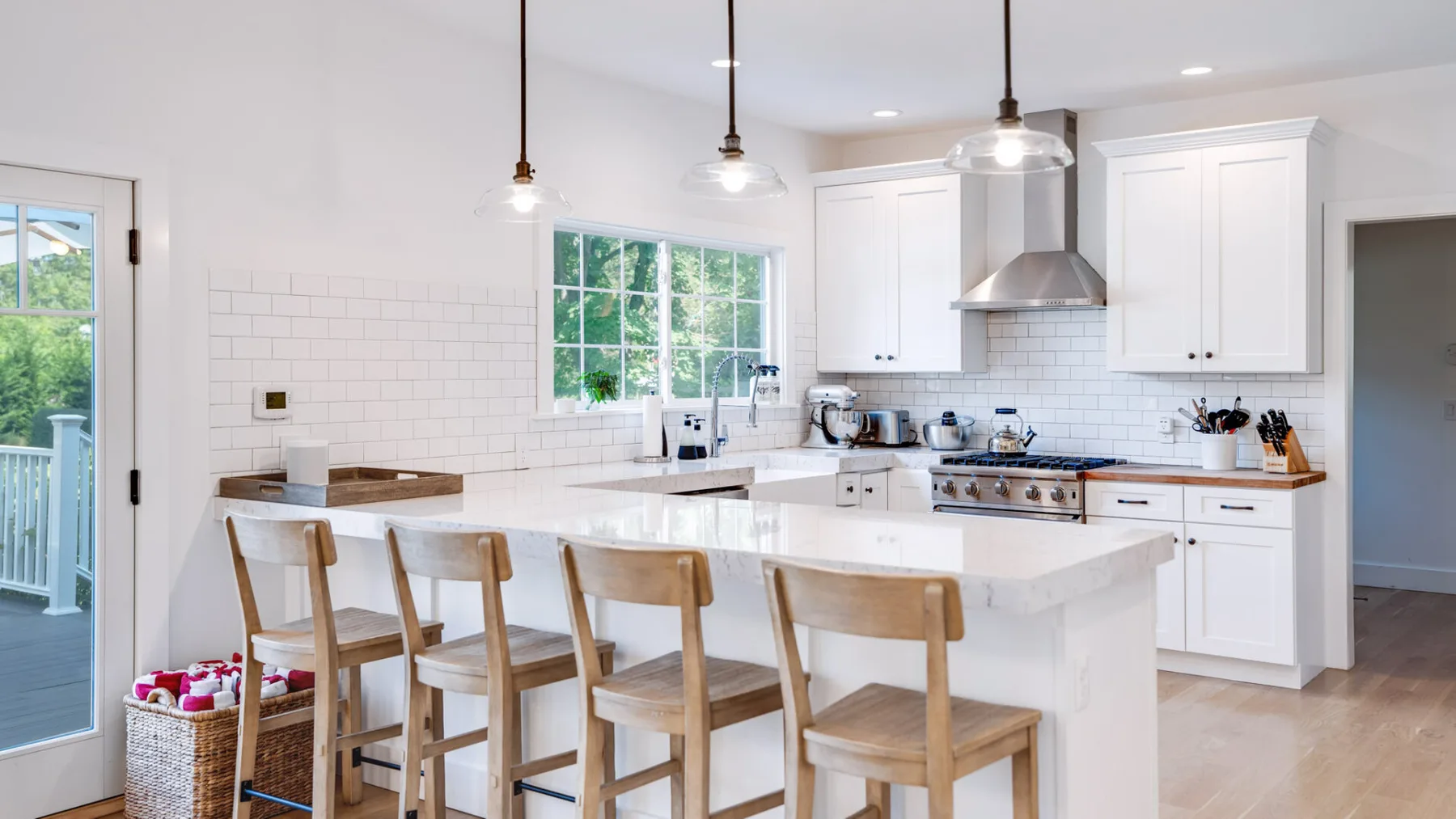 Una cocina luminosa con gabinetes blancos, una isla central y asientos de madera.