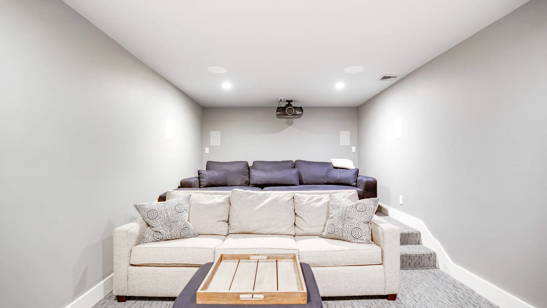 Una sala luminosa con un sofá crema frente a una zona elevada para sentarse.