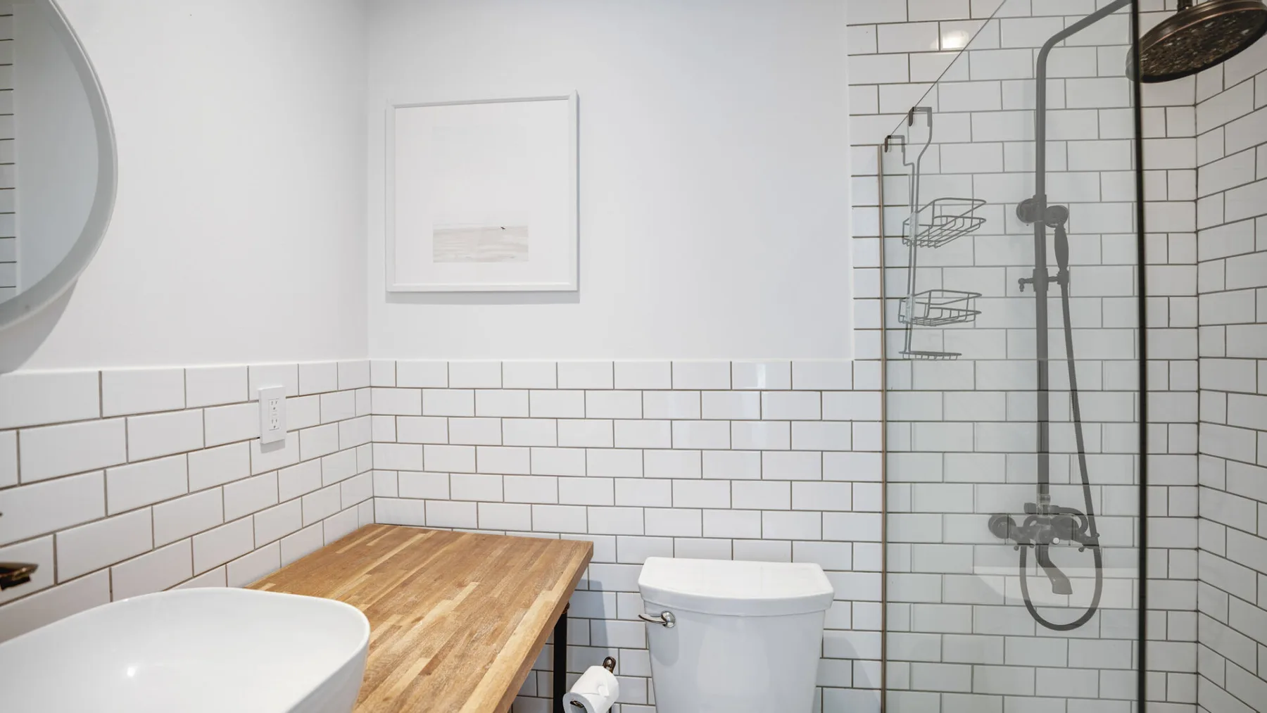 Un baño con ducha alicatada, inodoro y encimera de madera.