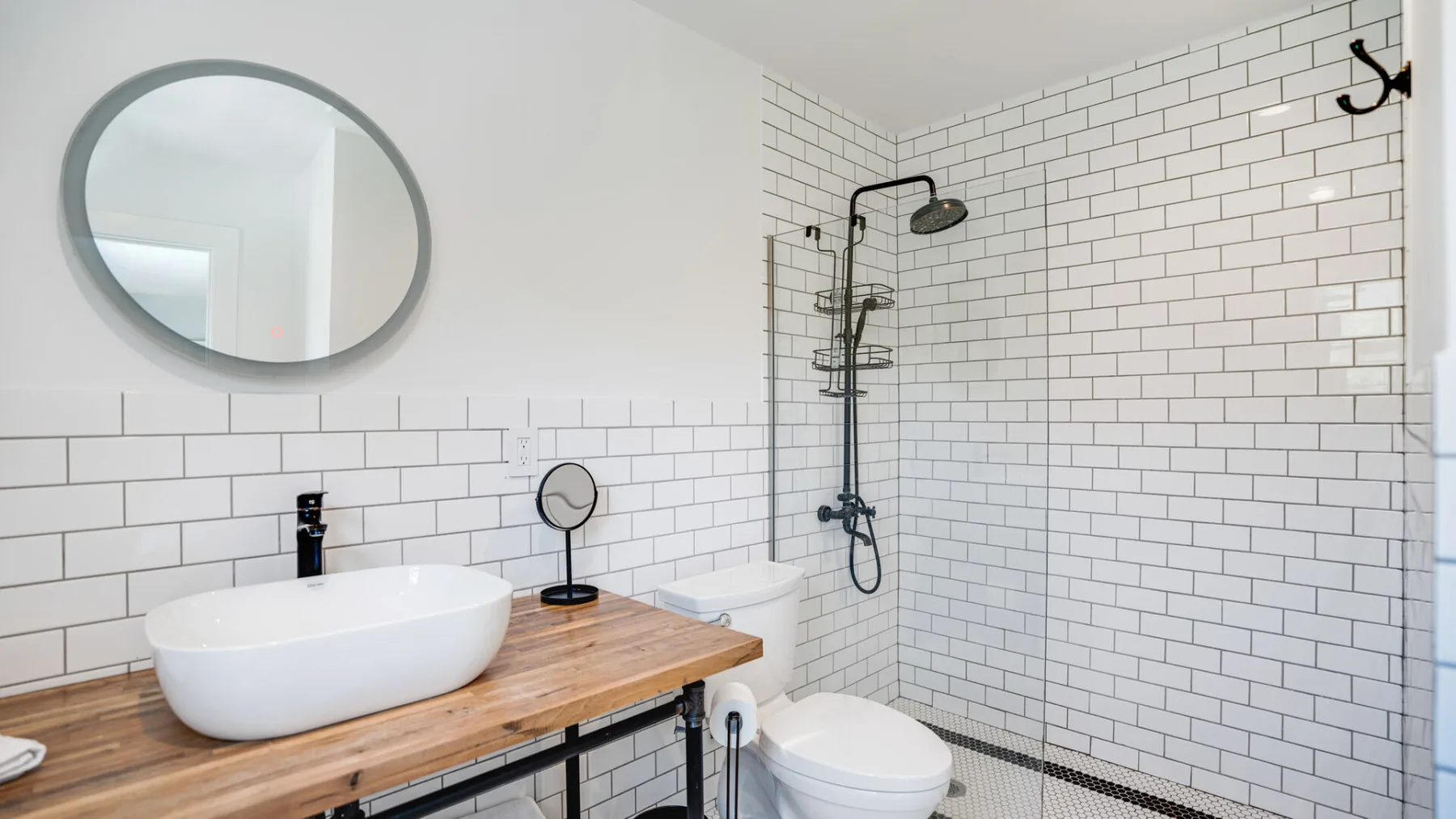 Un baño luminoso con azulejos, lavabo, espejo y ducha.