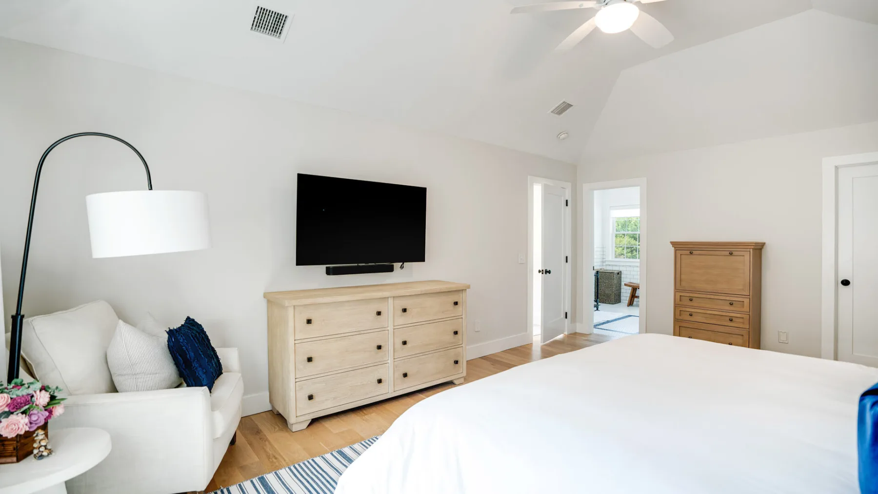 Un dormitorio luminoso con una cama, una cómoda y un televisor.