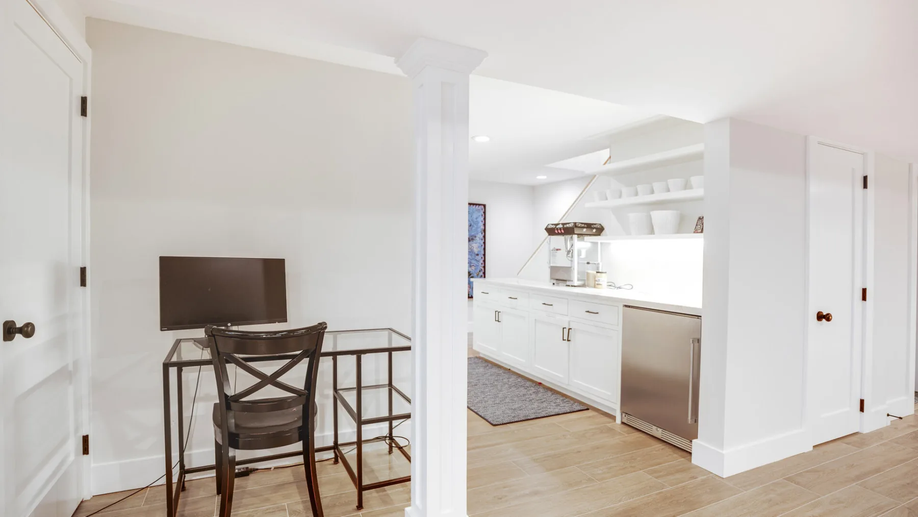 Una luminosa cocina abierta con zona de comedor, armarios blancos y una mesa pequeña.