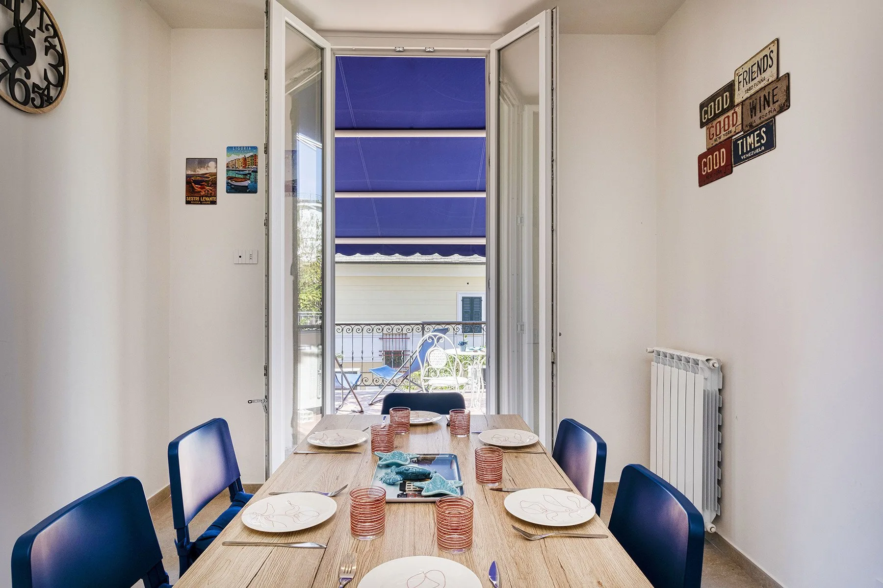 Comedor con una mesa larga de madera puesta con platos y asientos azules.
