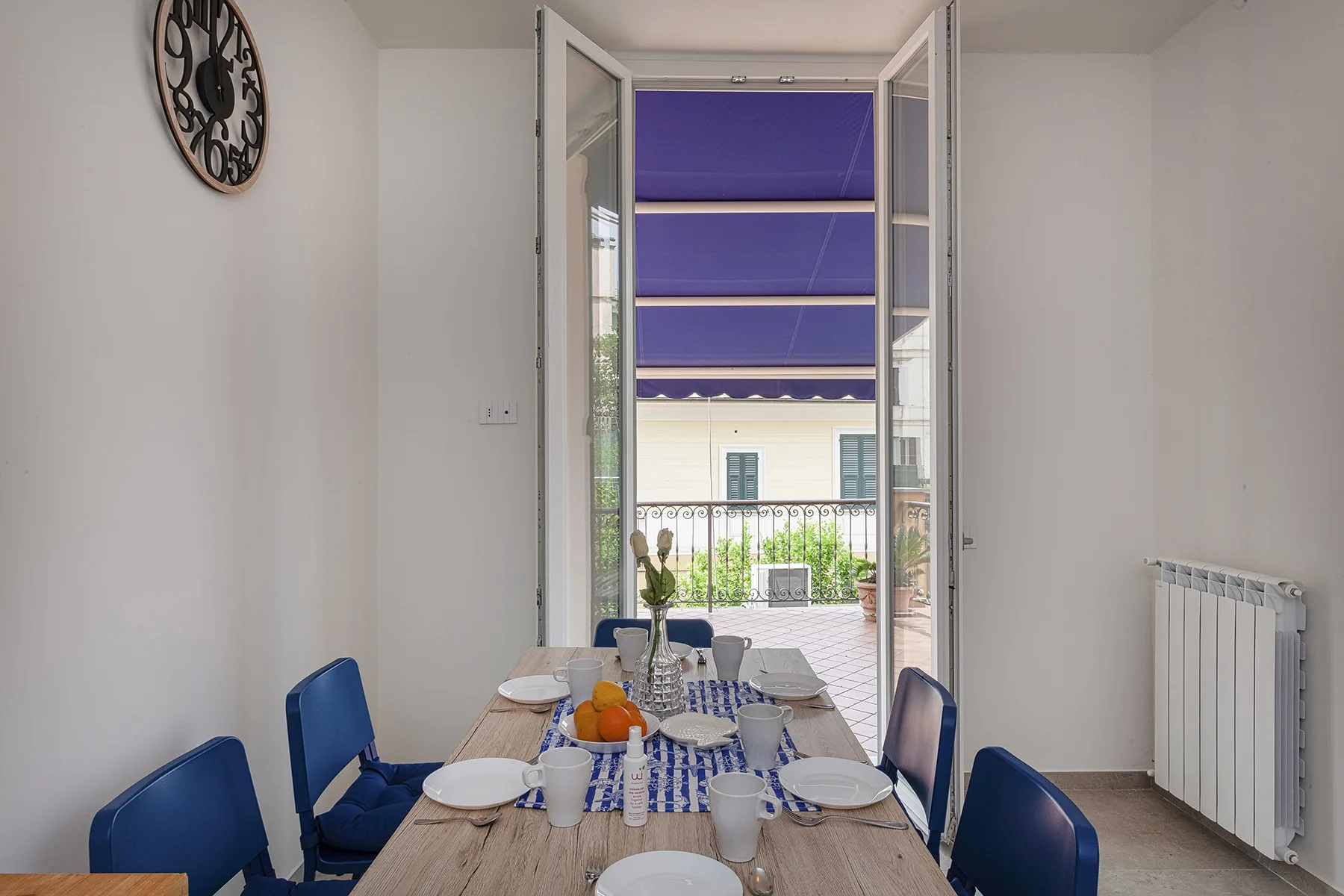 Comedor con una mesa puesta junto a puertas abiertas que dan a una terraza.