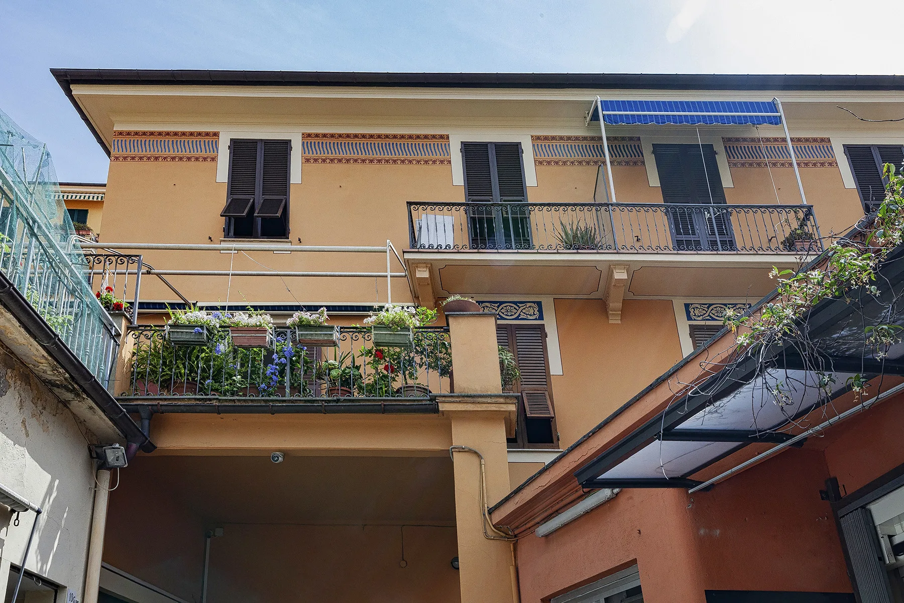 Vista exterior de un edificio color durazno con balcones y plantas.