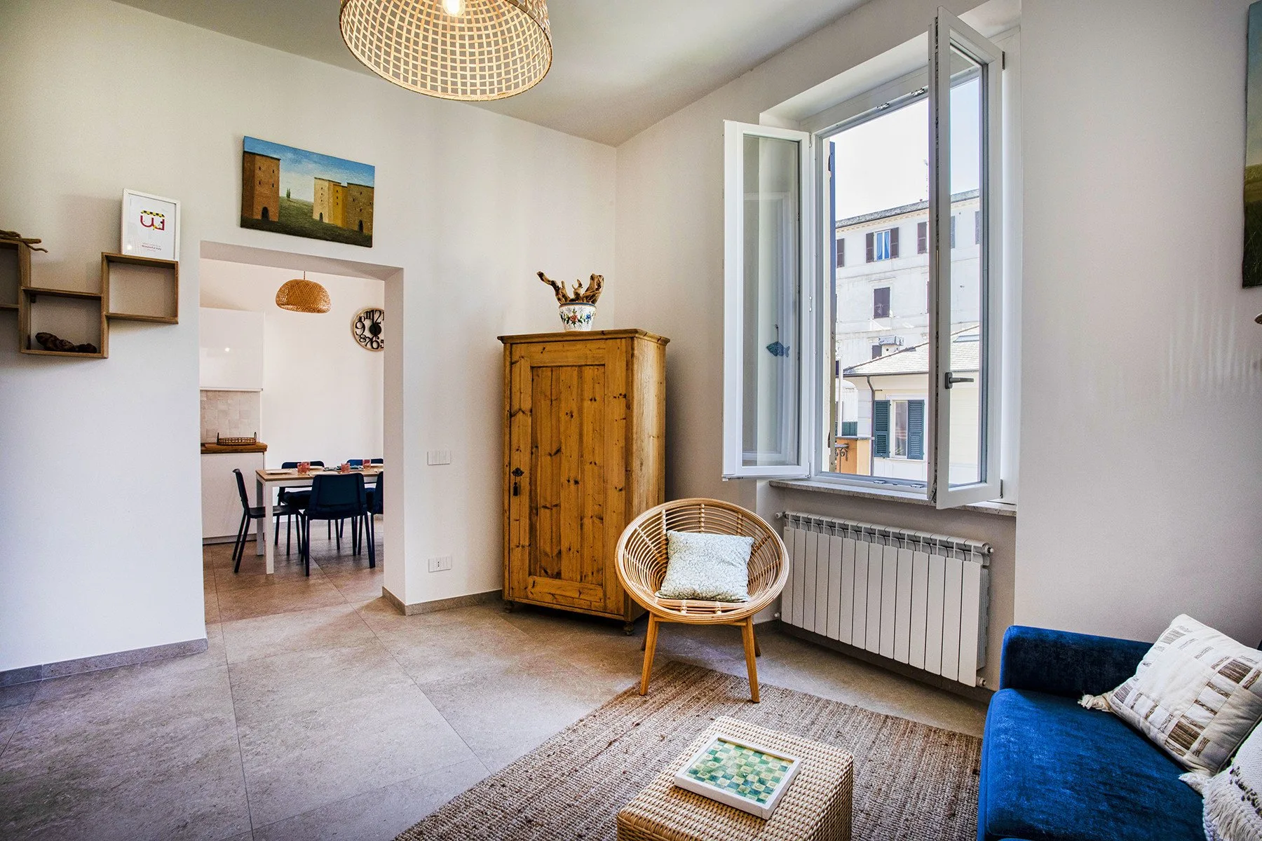 Una sala luminosa con una zona de estar junto a una ventana abierta.