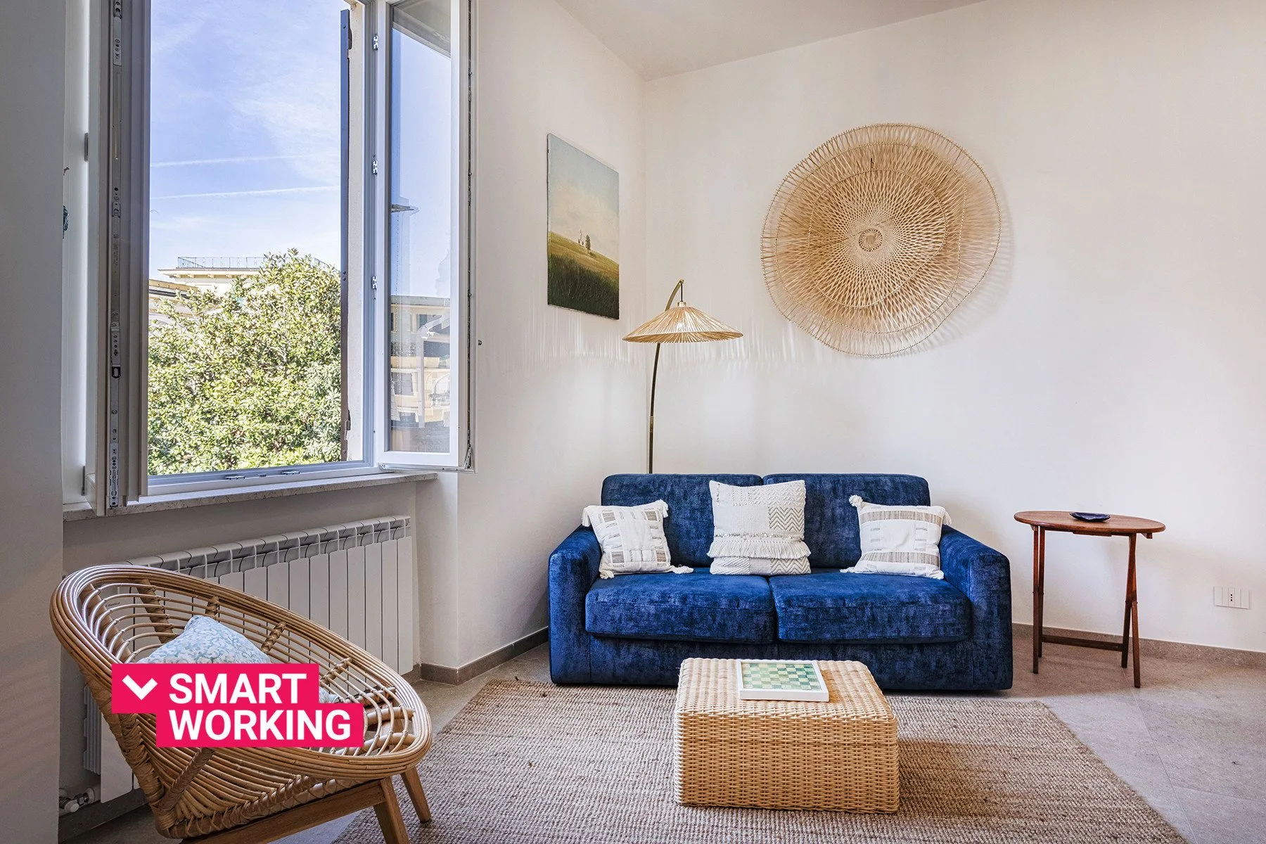 Una sala luminosa con asientos azules, una mesa de centro tejida y una ventana abierta.
