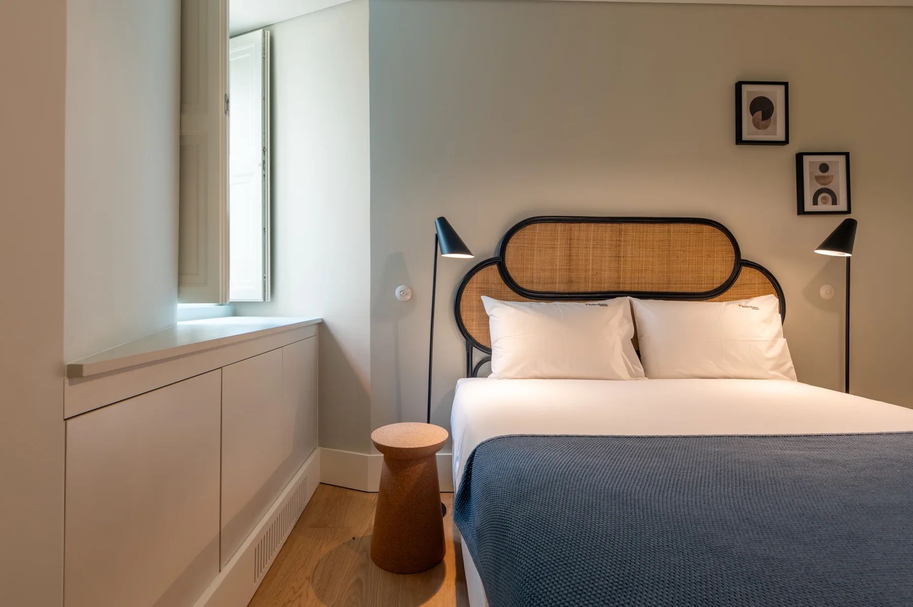 A bedroom with a bed, bedside lamps, and a window.