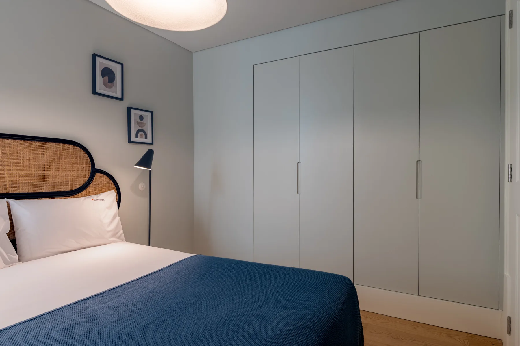 A bedroom with a bed, blue bedspread, and built-in wardrobes.