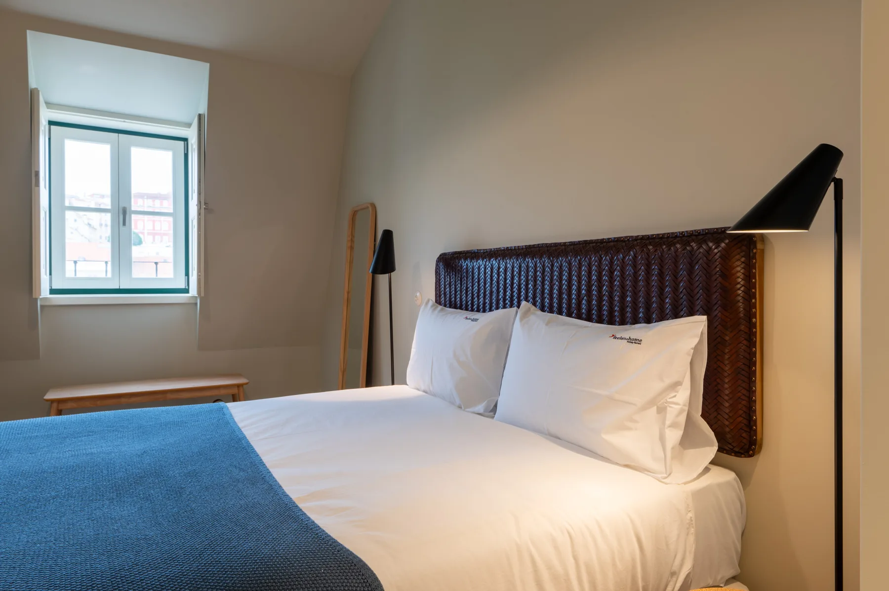 A bedroom with a neatly made bed and a window.