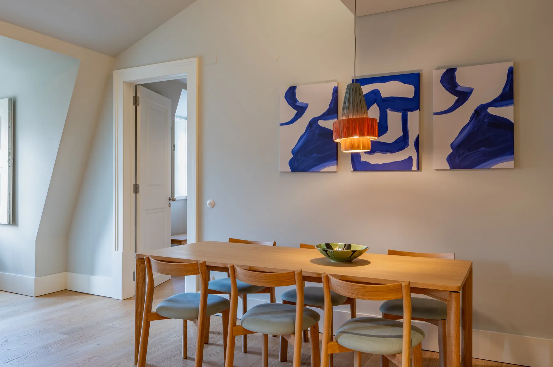 A dining area with a wooden table, seating, and abstract artwork on the wall.