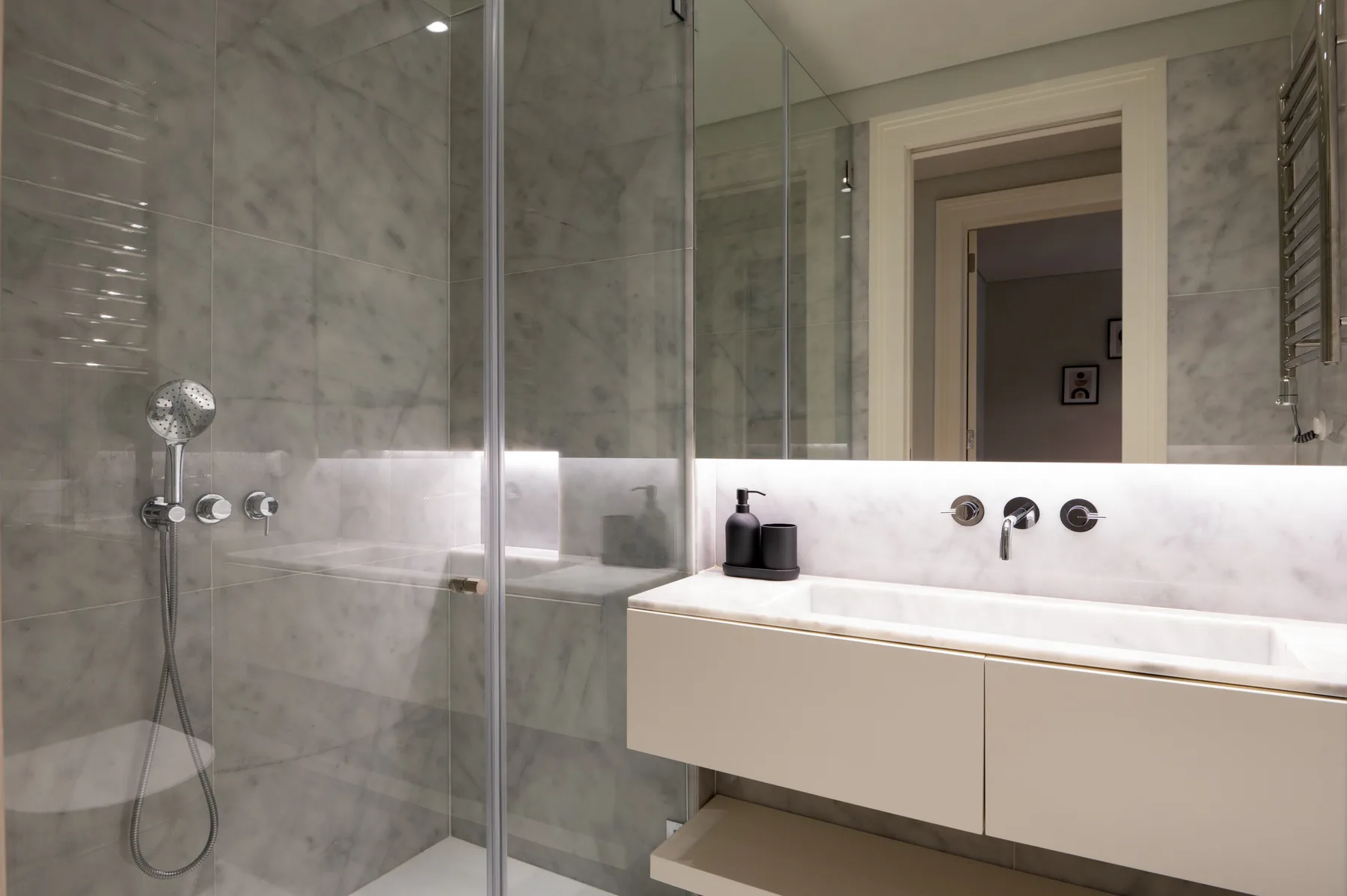 A modern bathroom with a glass shower and a wide sink counter.