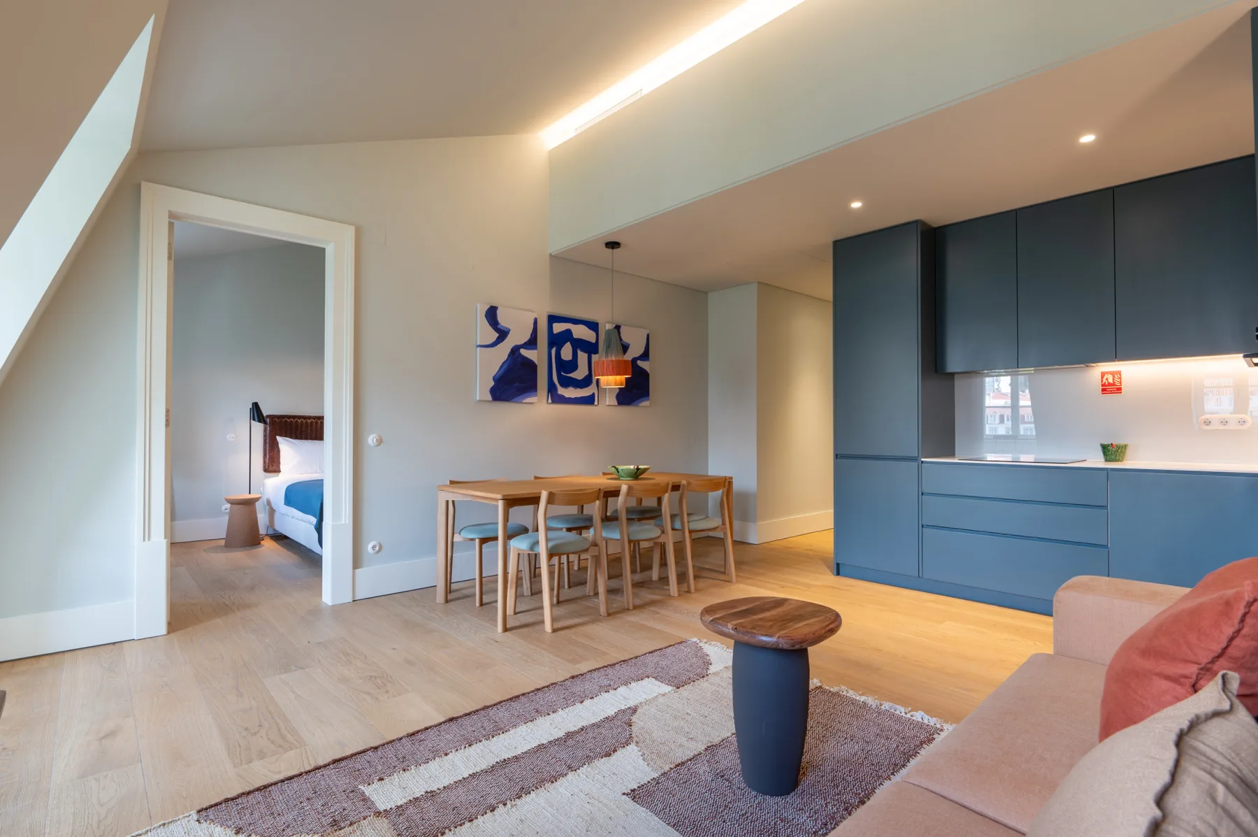 An open-plan living and dining area with blue kitchen cabinets and a dining table.