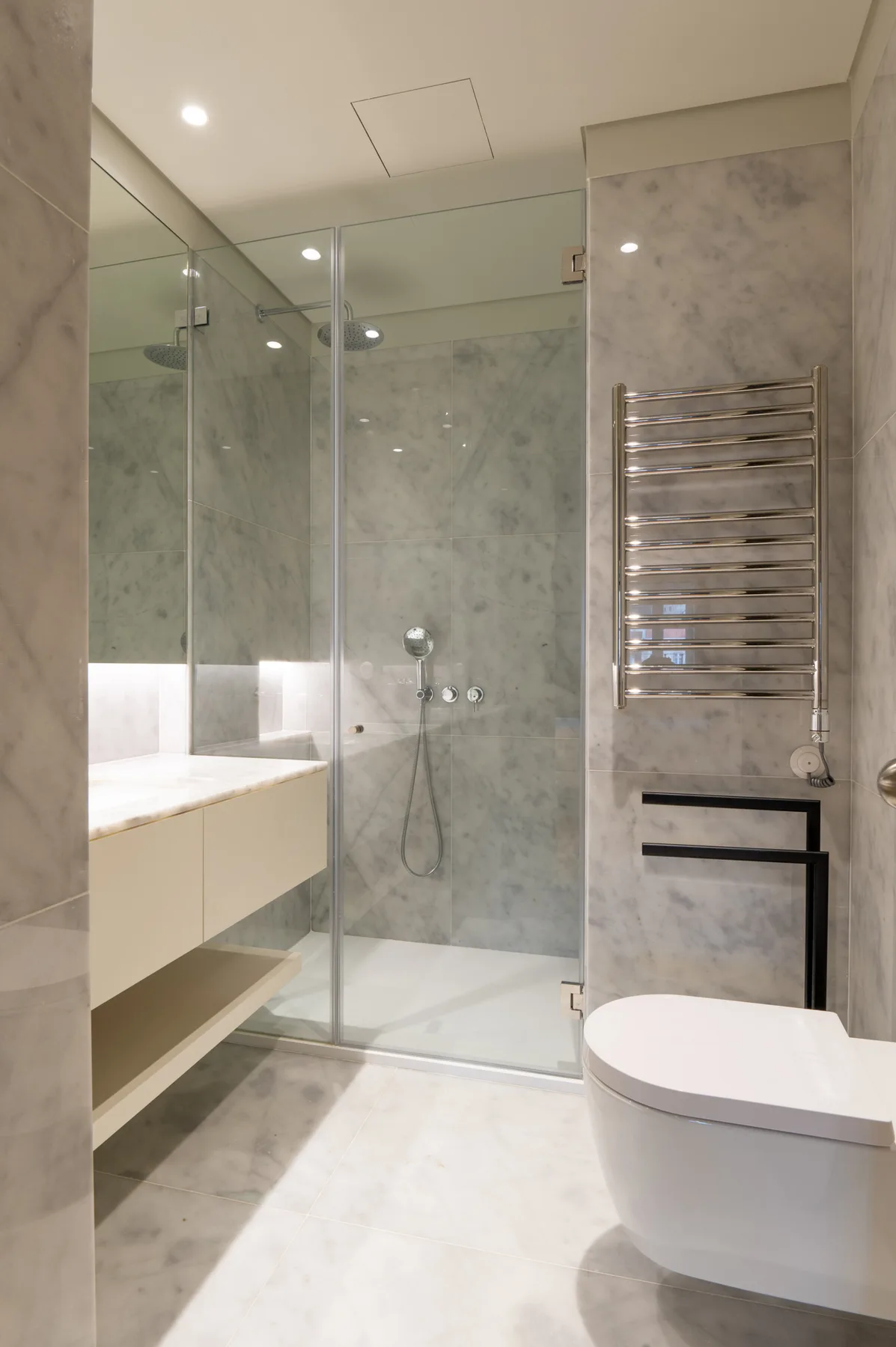 A modern bathroom with a glass shower and wall-mounted sink.