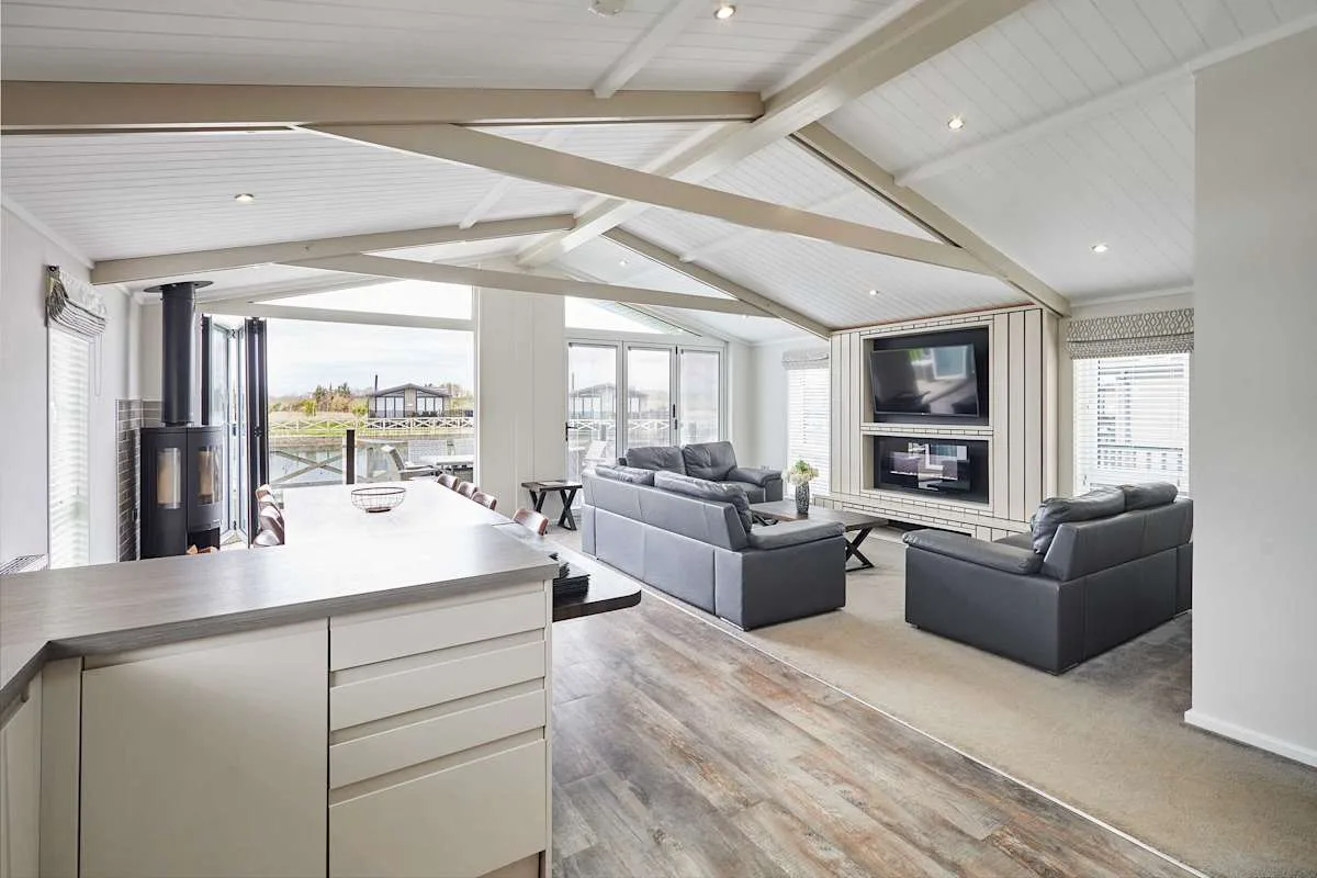 An open-plan living area with seating, a kitchen island, and large windows.