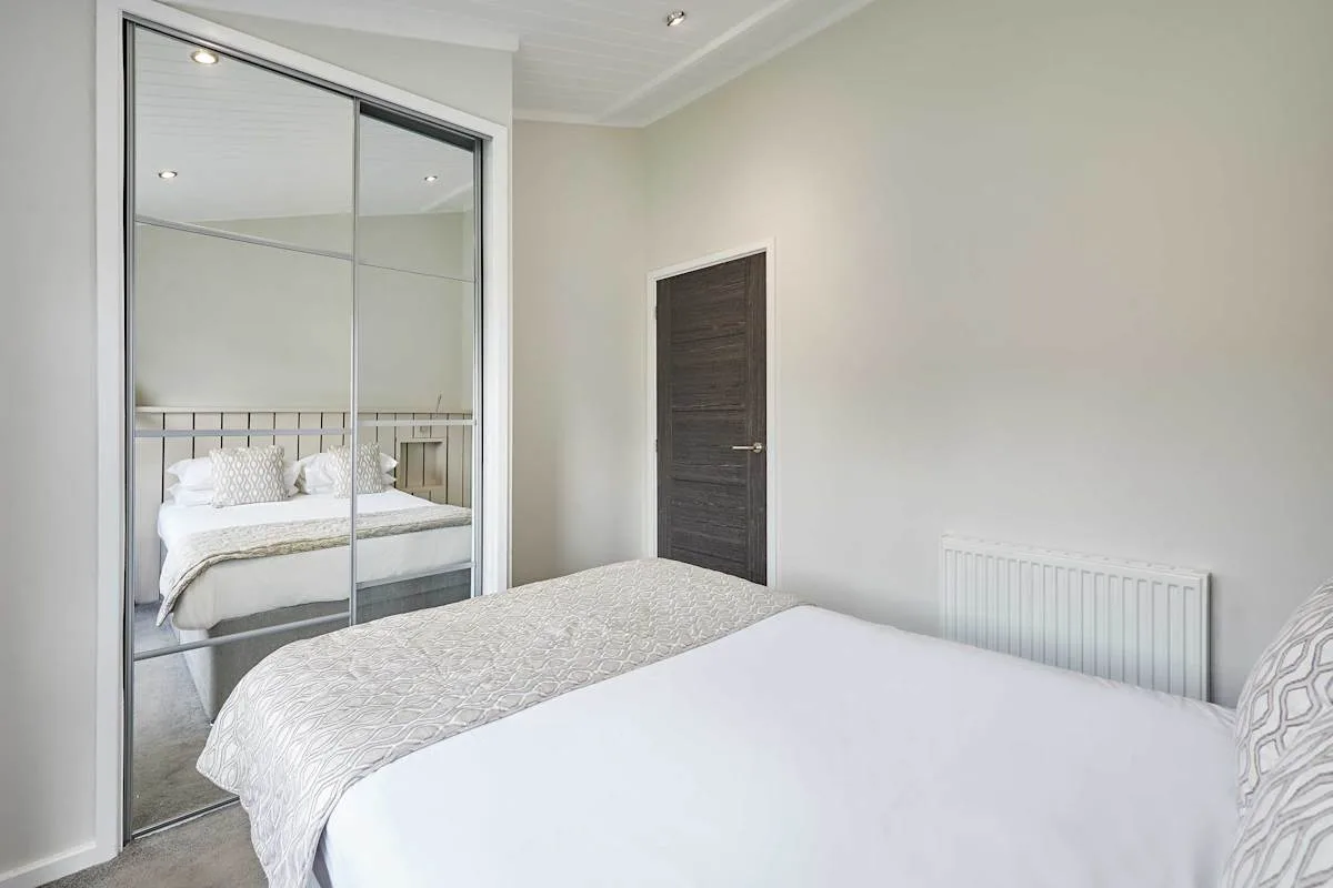 A bright bedroom with a bed and mirrored wardrobe doors.