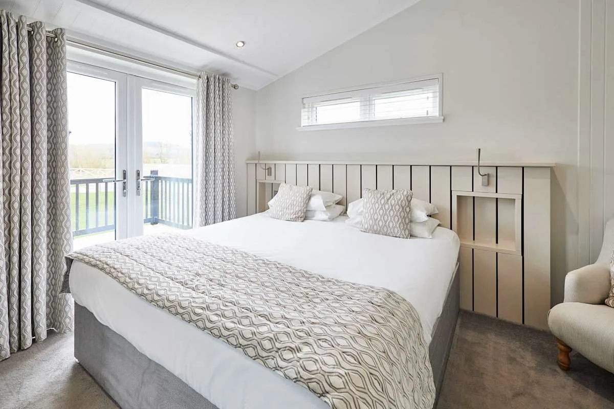 A bright bedroom with a large bed and glass doors opening onto a balcony.