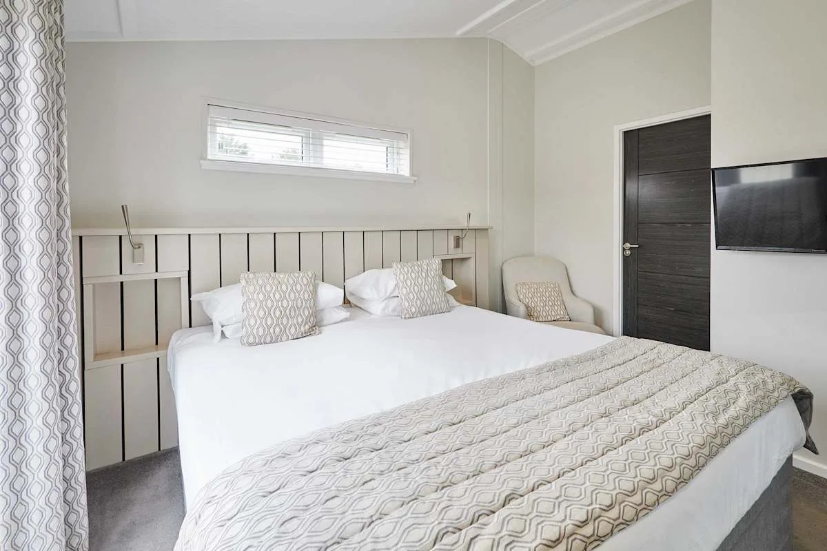 A bedroom with a large bed, patterned bedding, and a wall-mounted television.