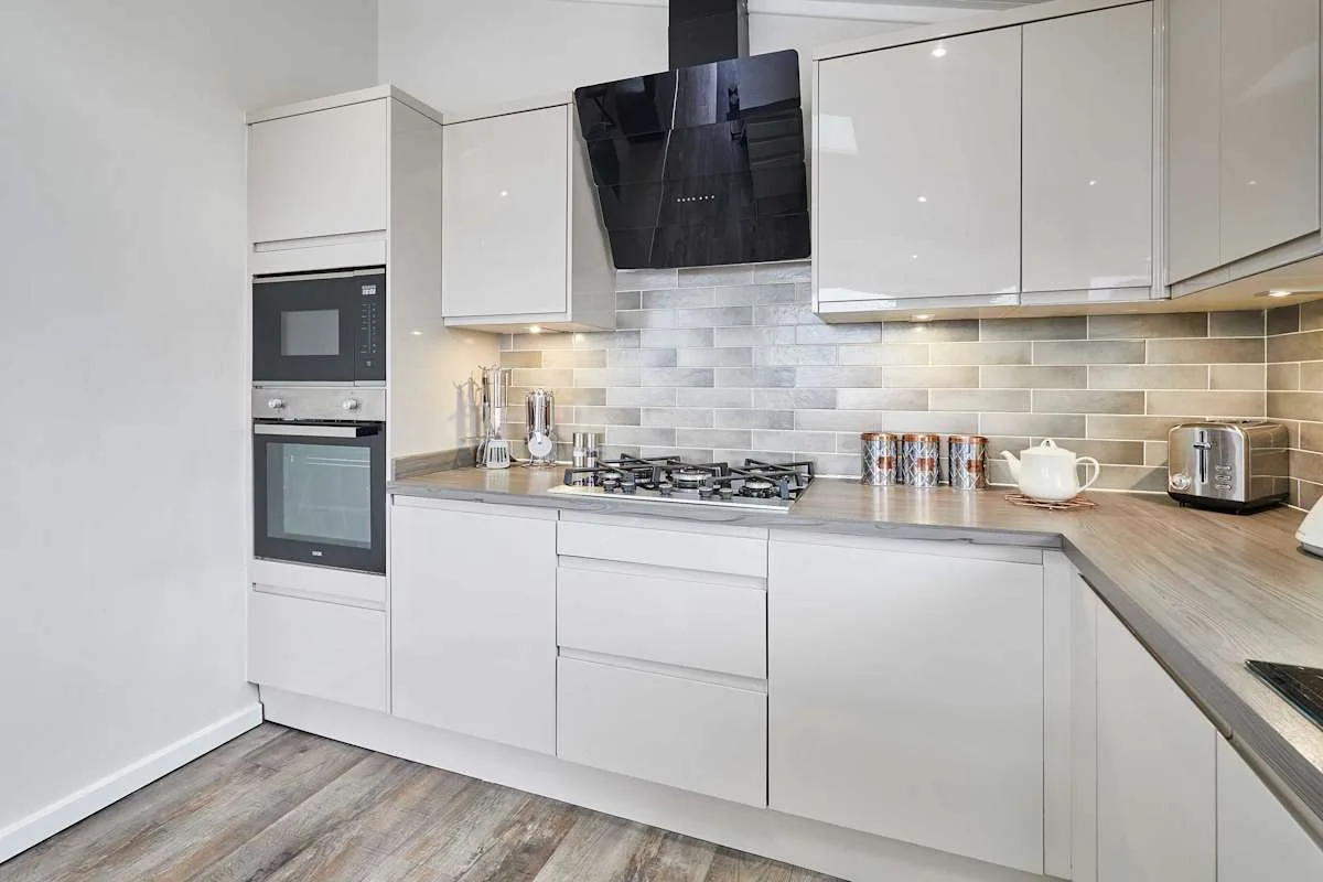 A modern kitchen with white cabinets and a stovetop.