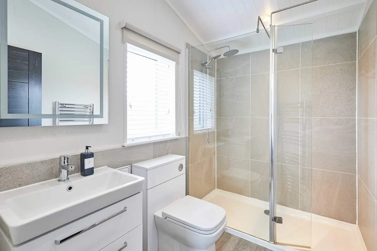 A bright bathroom with a sink, toilet, and glass shower.