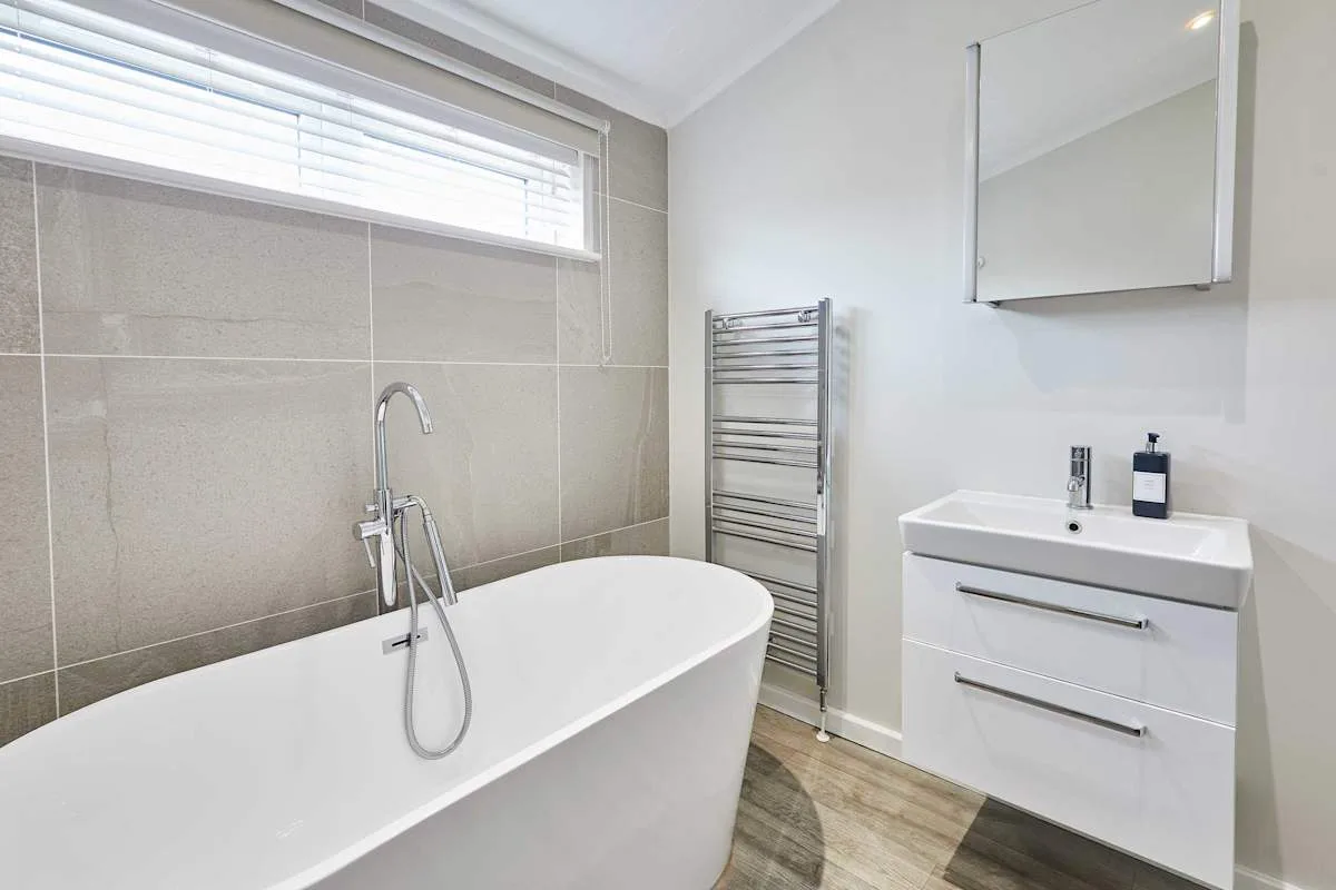 A bathroom with a freestanding bathtub, towel warmer, and vanity.